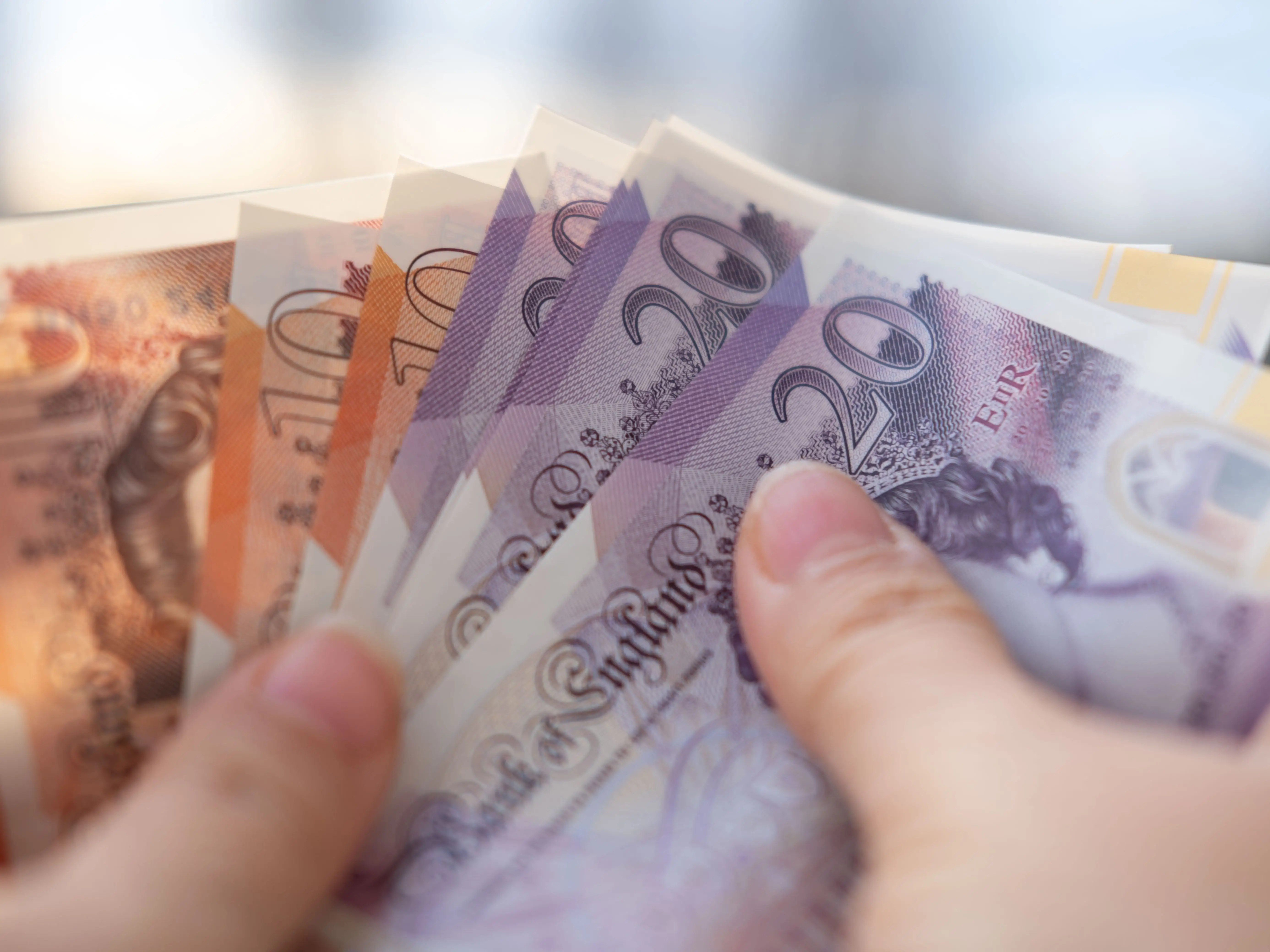 Close-up of a hand holding UK bills.