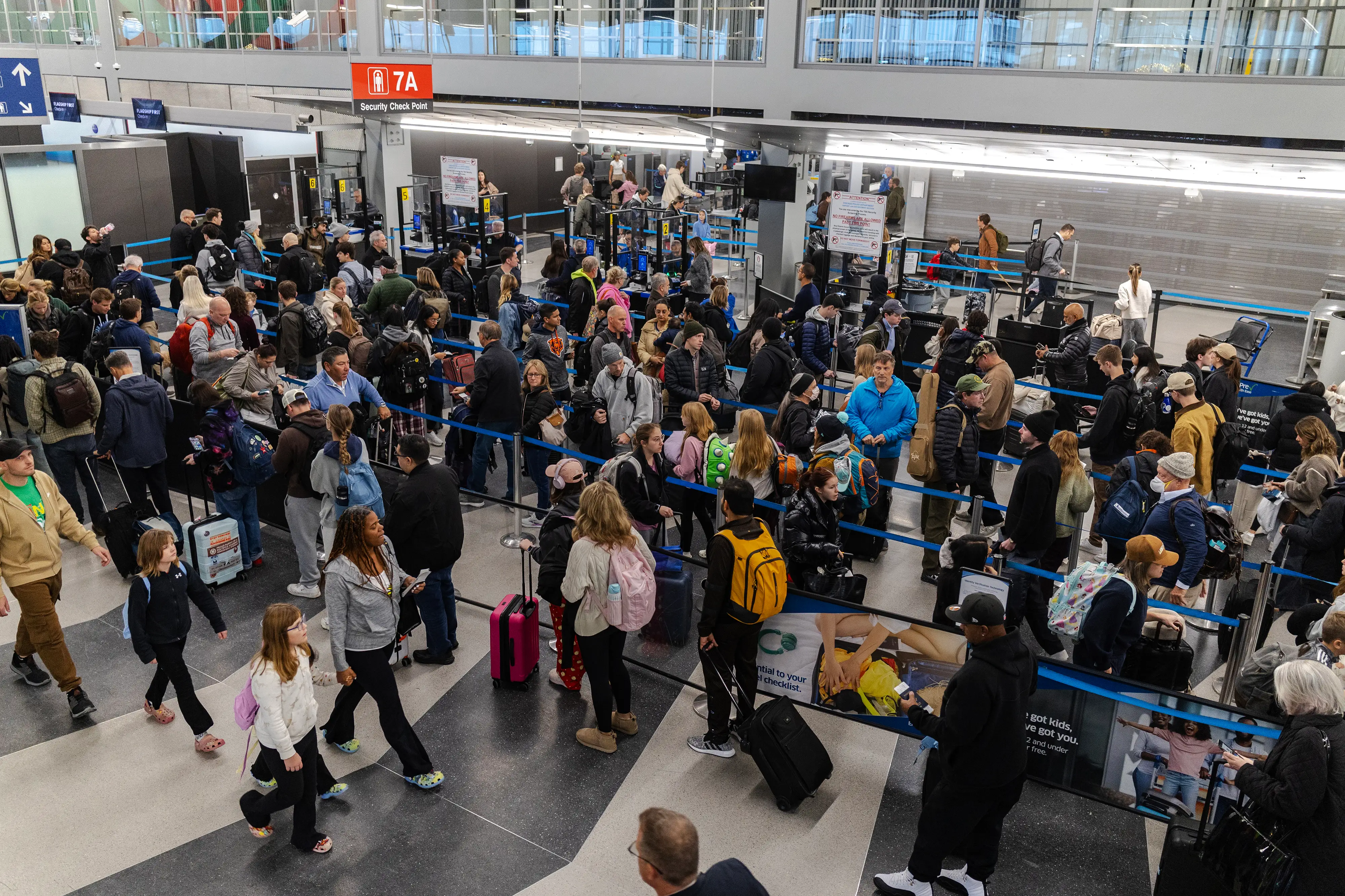 Travelers wait in line at a security checkpoint in Terminal 3 at O'Hare International airport on November 30, 2025 in Chicago,