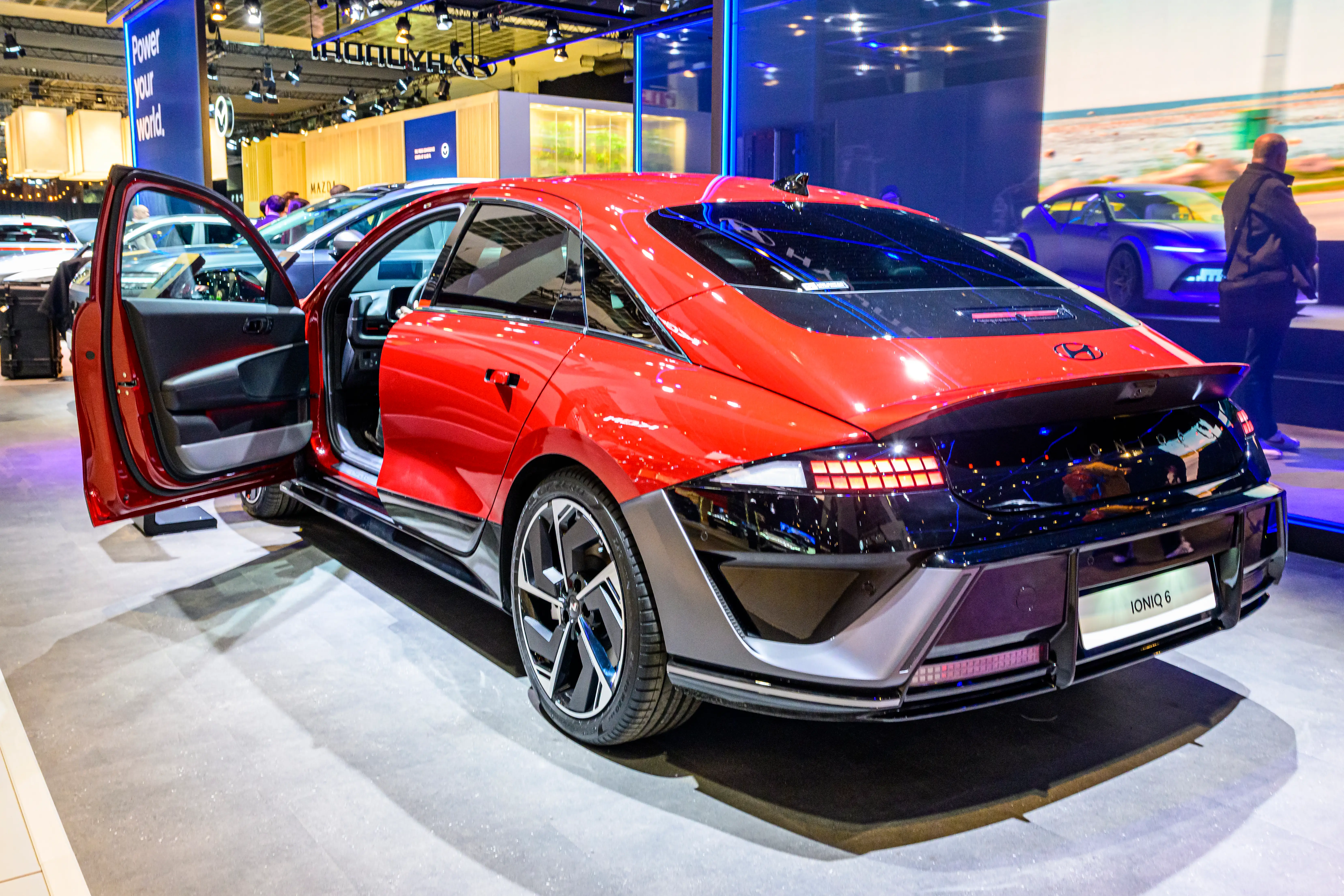 A red Hyundai Ioniq 6 Standard is parked on a showroom floor. The driver's door is open, and the handles are popped out.