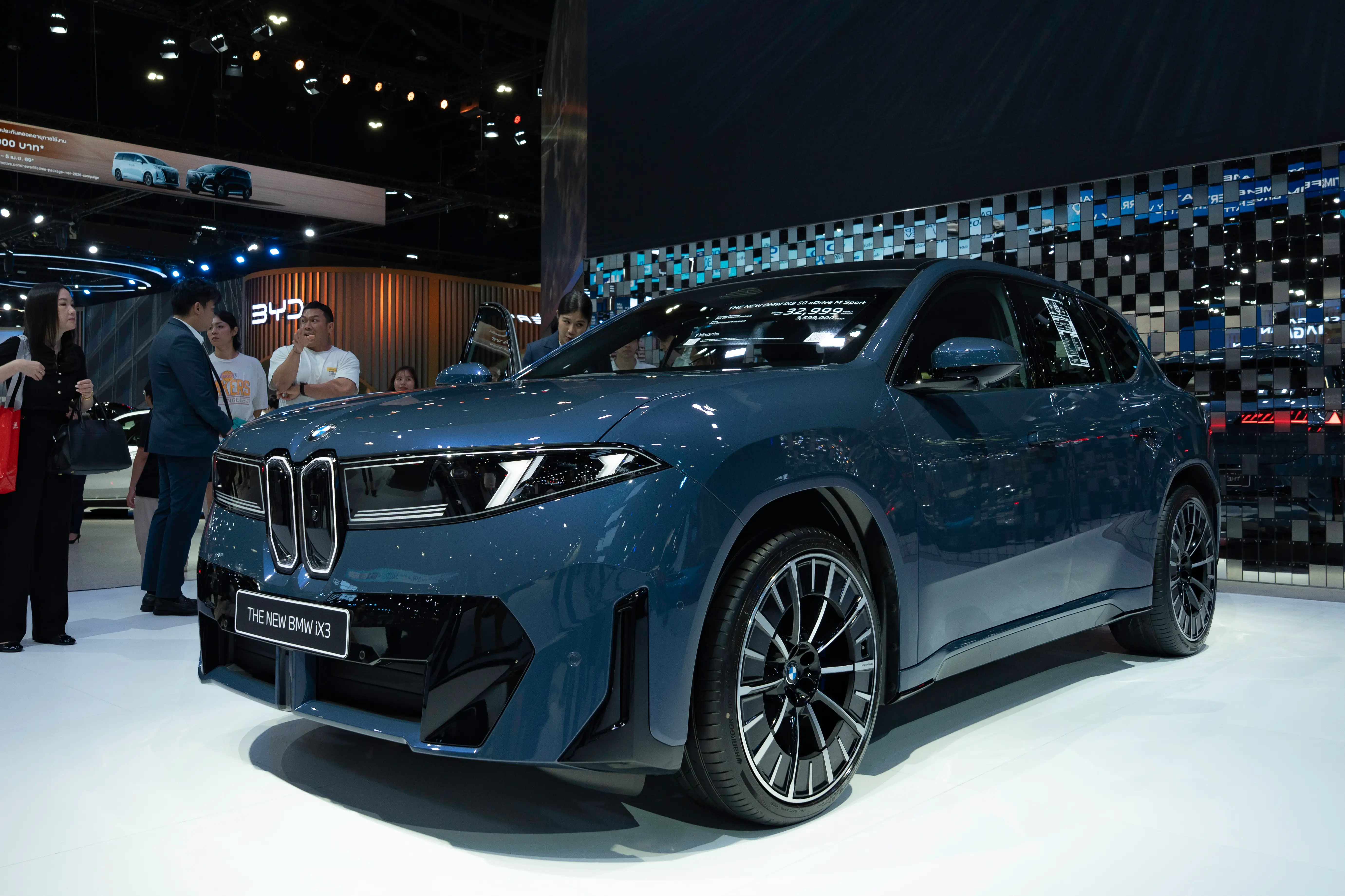 A blue BMW iX SUV is parked on a white showroom floor.