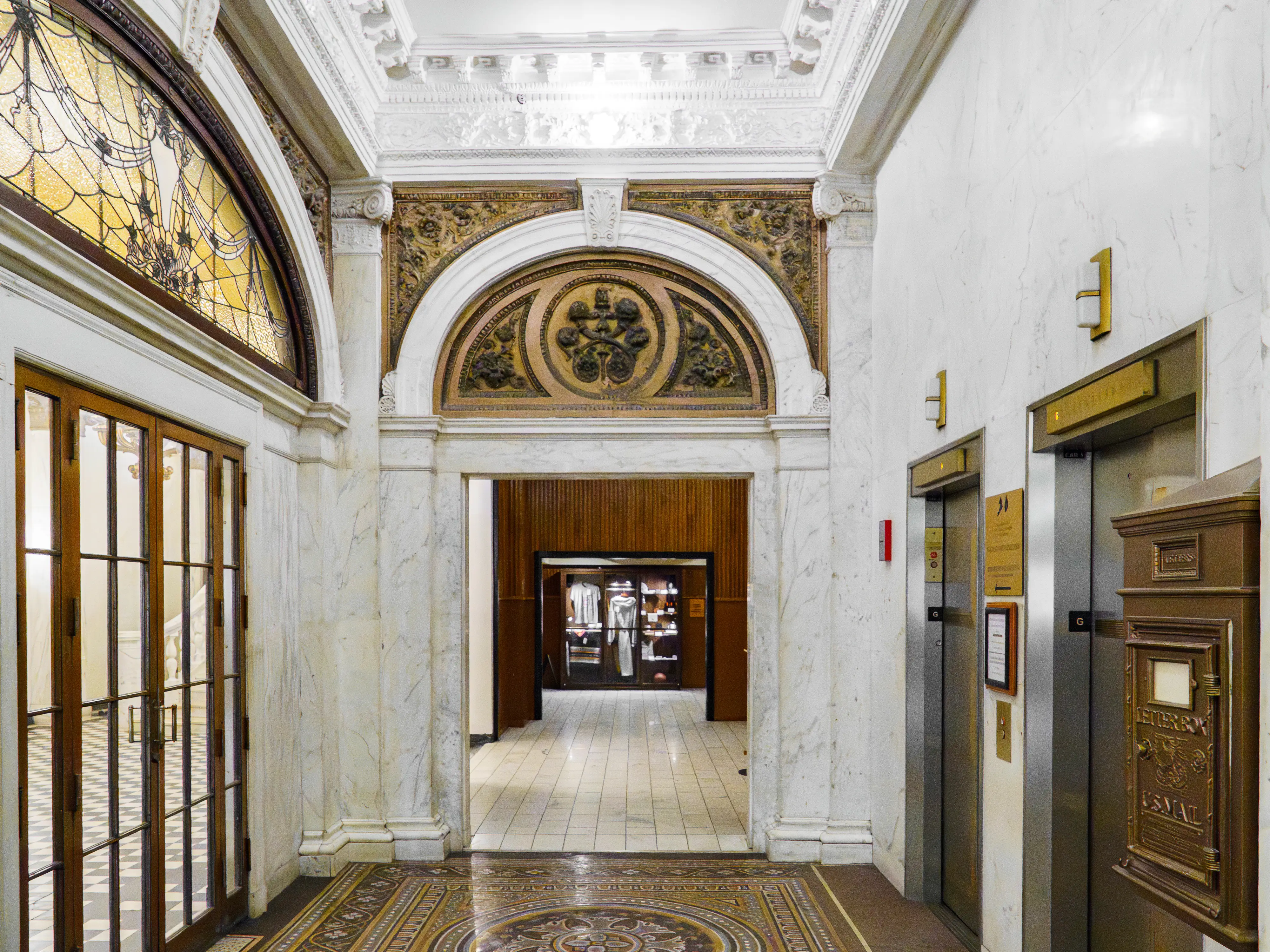 Inside the hotel, there are intricate moldings on the walls and elevators on the right