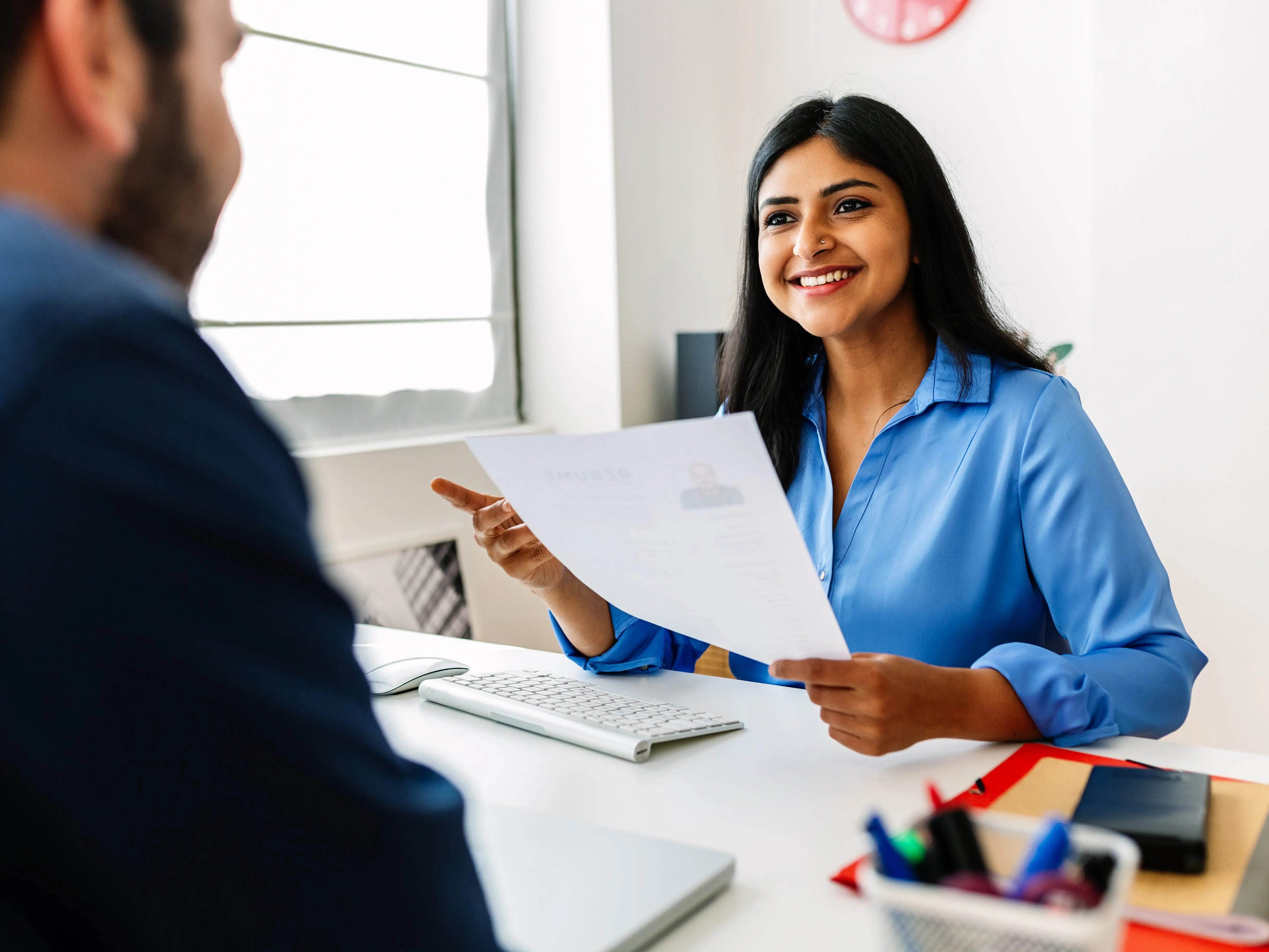 An HR recruitment manager holding someone's résumé while looking at someone