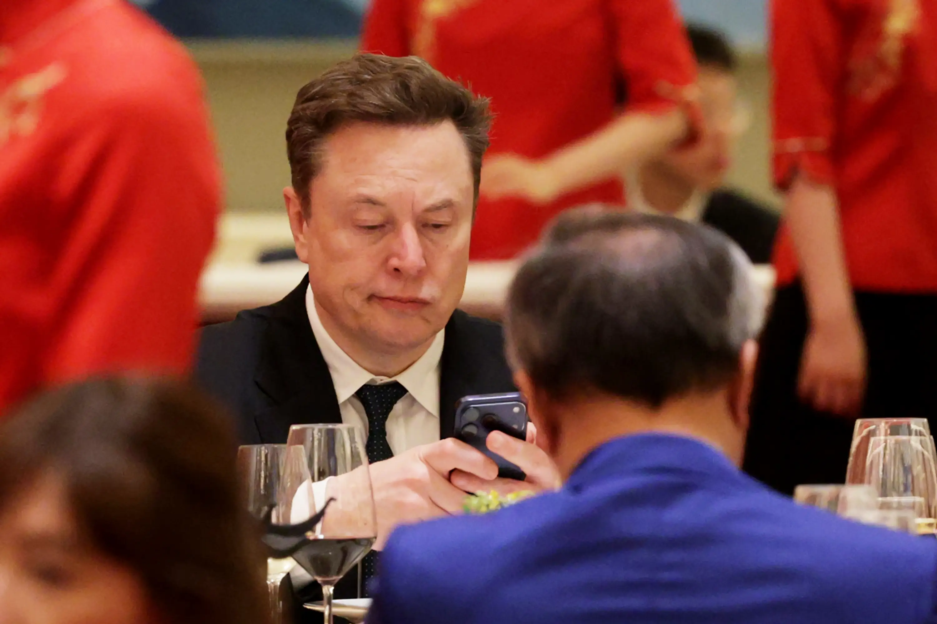 SpaceX and Tesla CEO Elon Musk looks at his phone while attending a state banquet hosted by Chinese leader Xi Jinping.