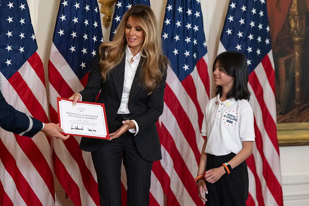 Melania Trump presents a certificate to a child at the Presidential AI Challenge.