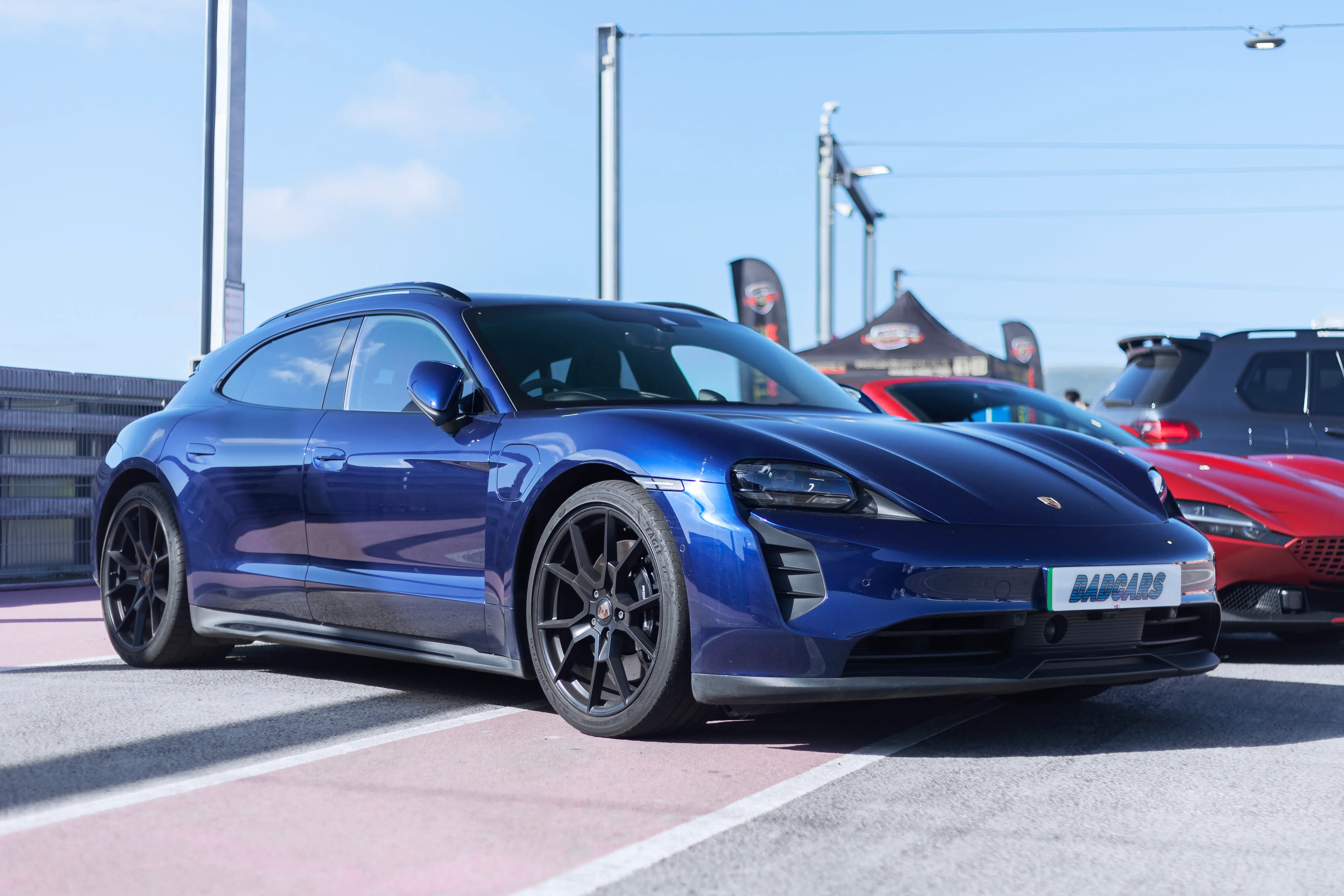 A blue Porsche Taycan wagon is parked on the tarmac.
