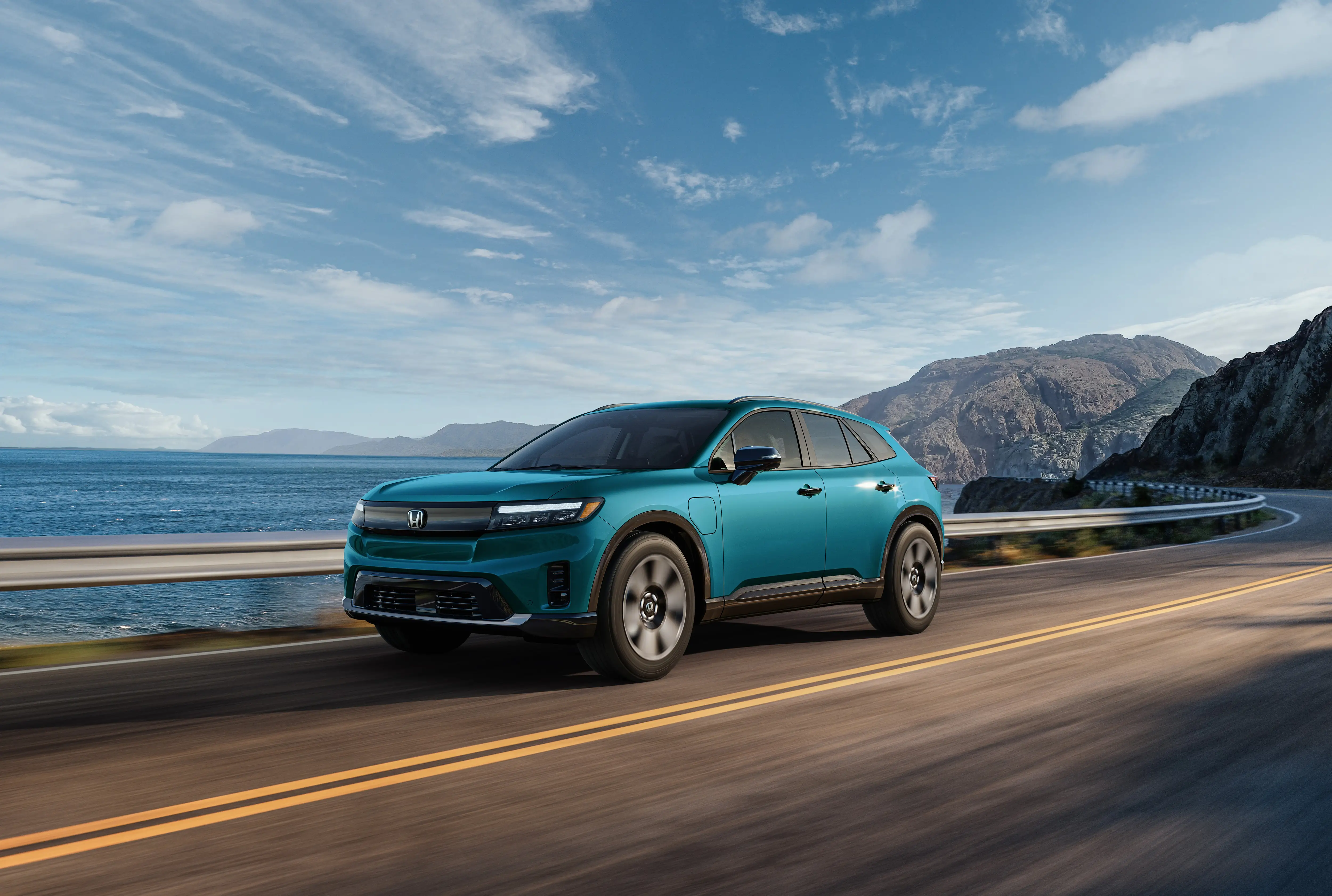 A teal blue Honda Prologue drives down a two-lane road.