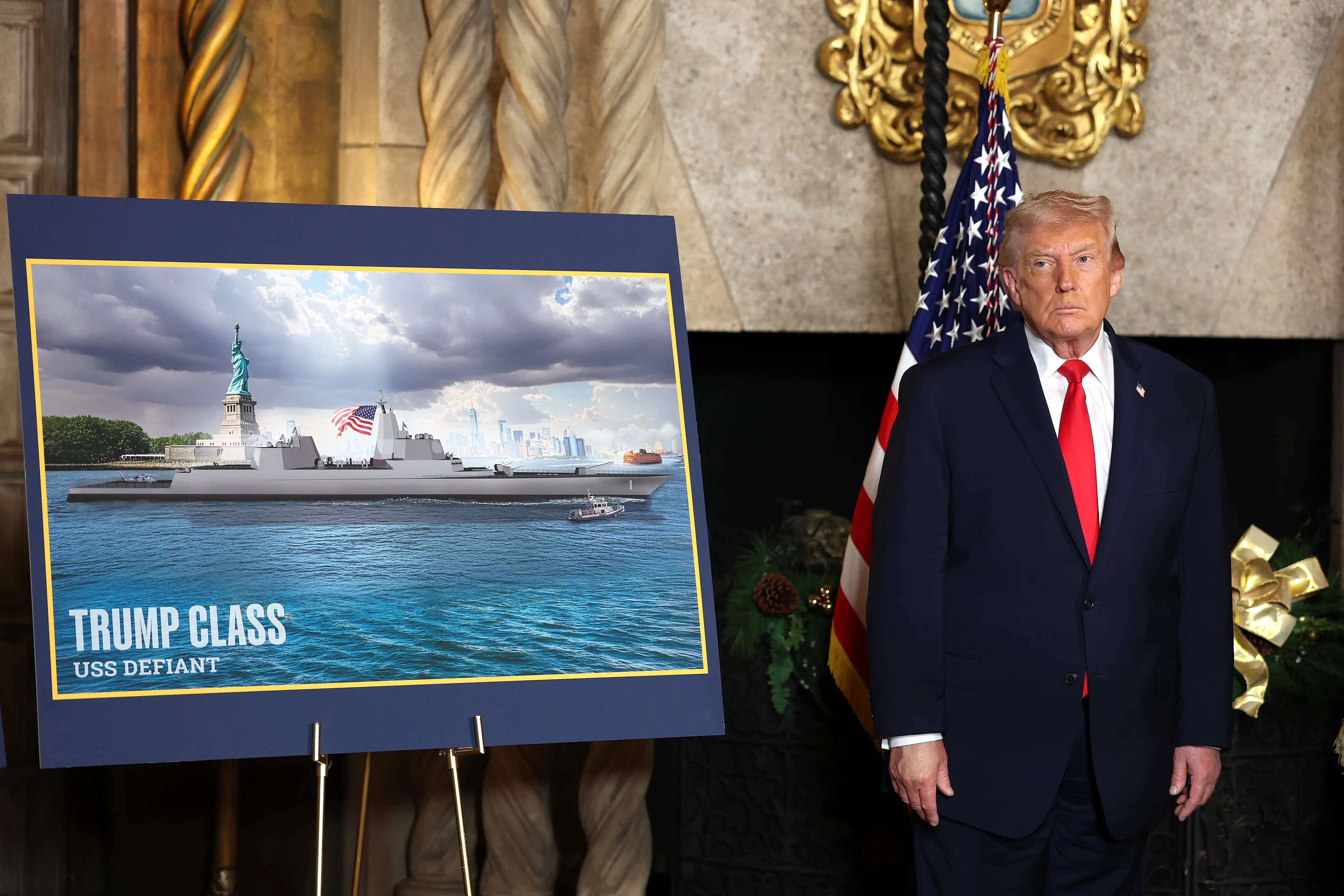 Donald Trump stands next to a sign showing a Trump-class ship.