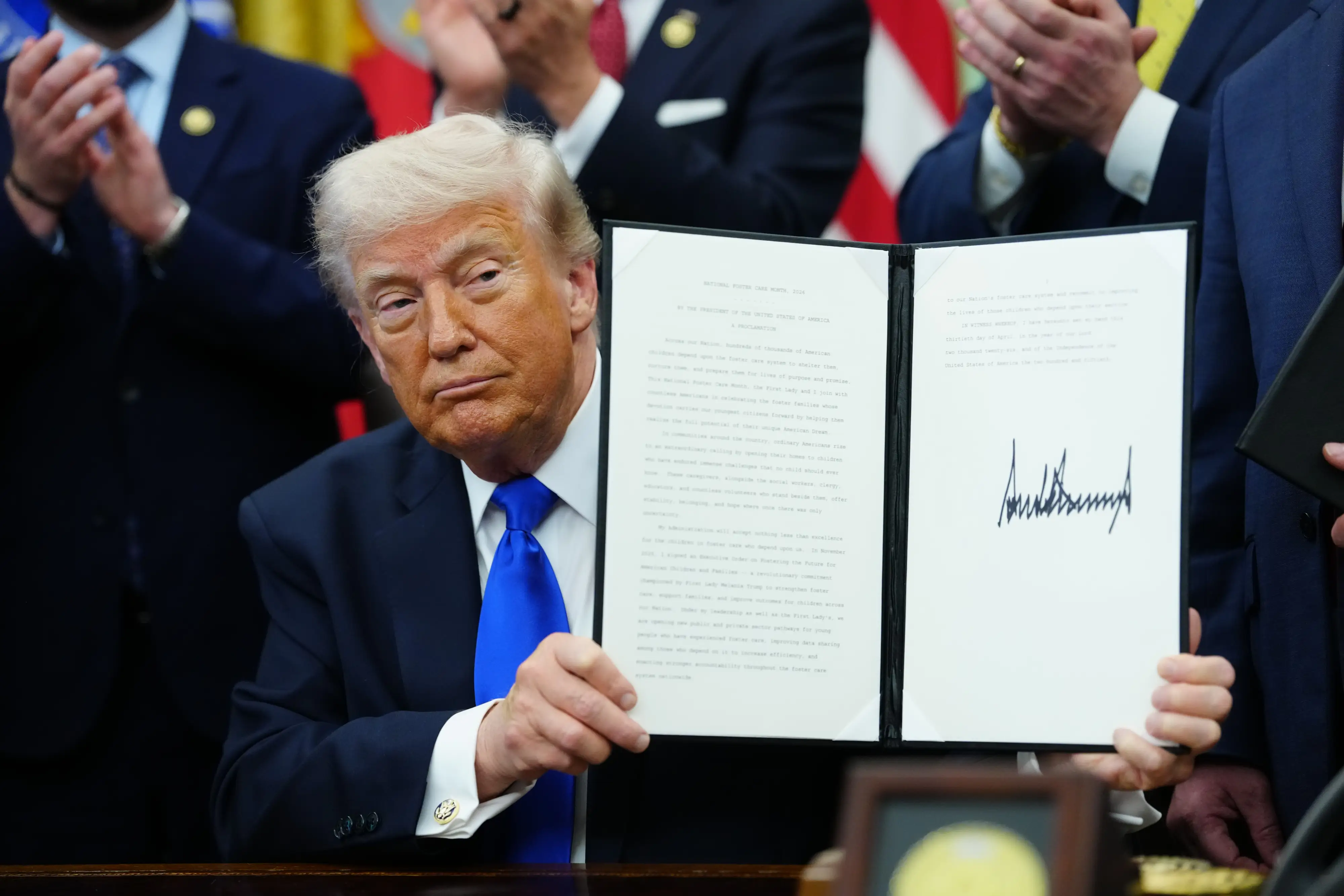 President Donald Trump displays a signed executive order in the Oval Office.