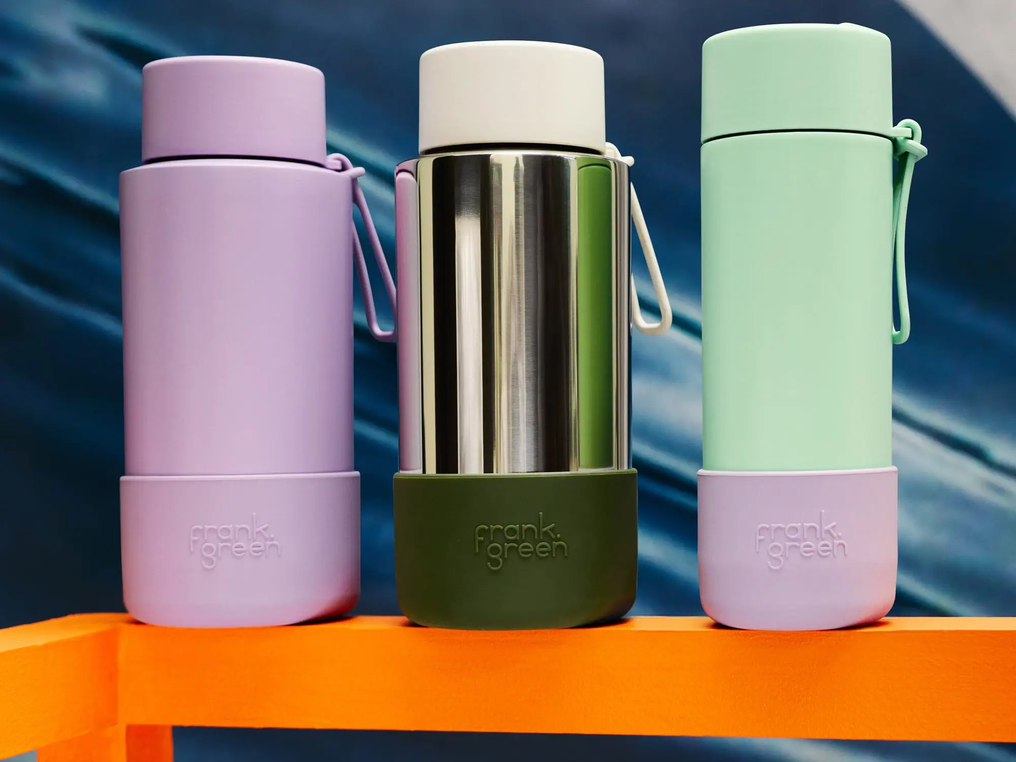 Three Frank Green water bottles in varying shades.