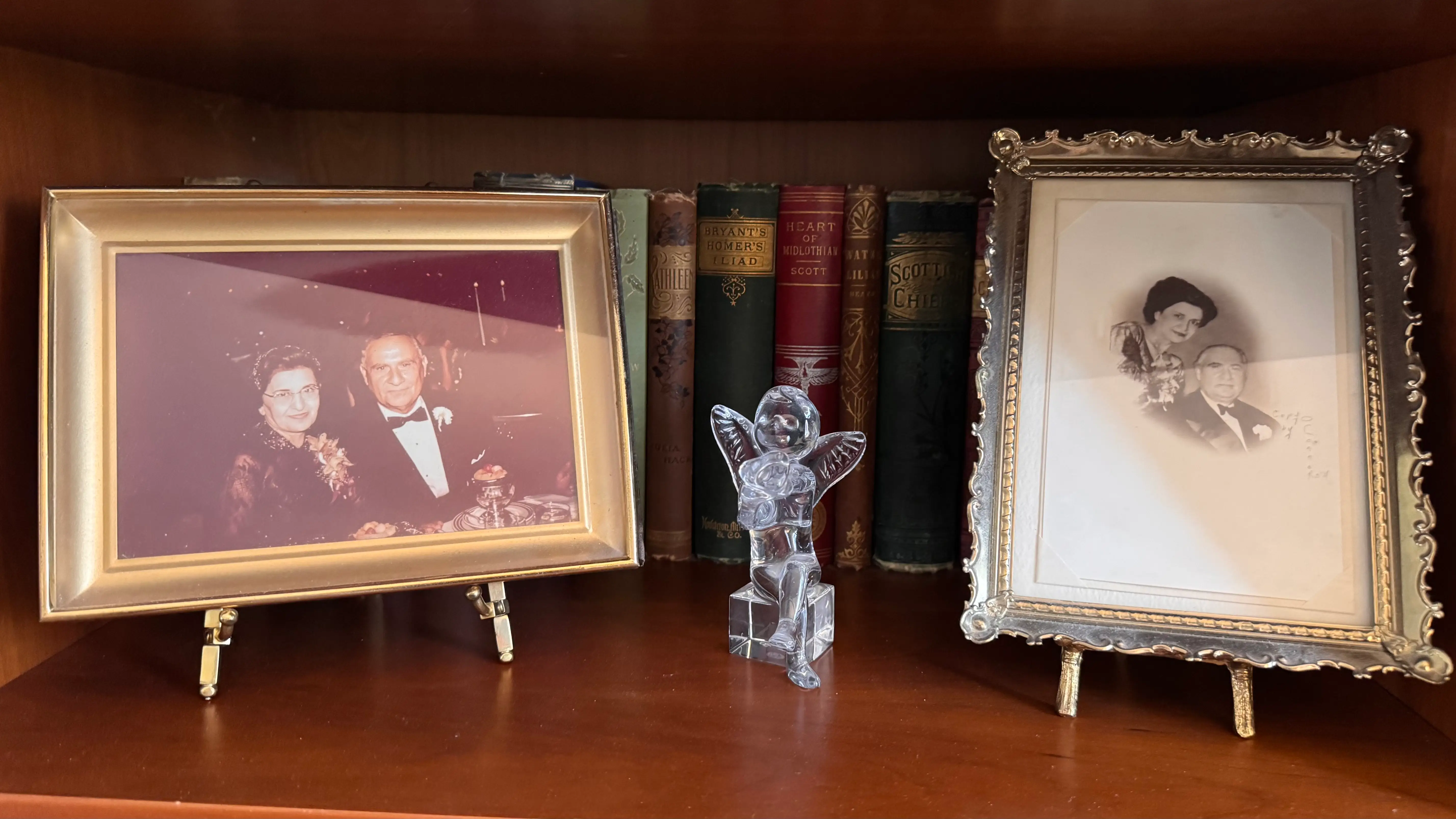 Framed photos and figurine on bookshelf