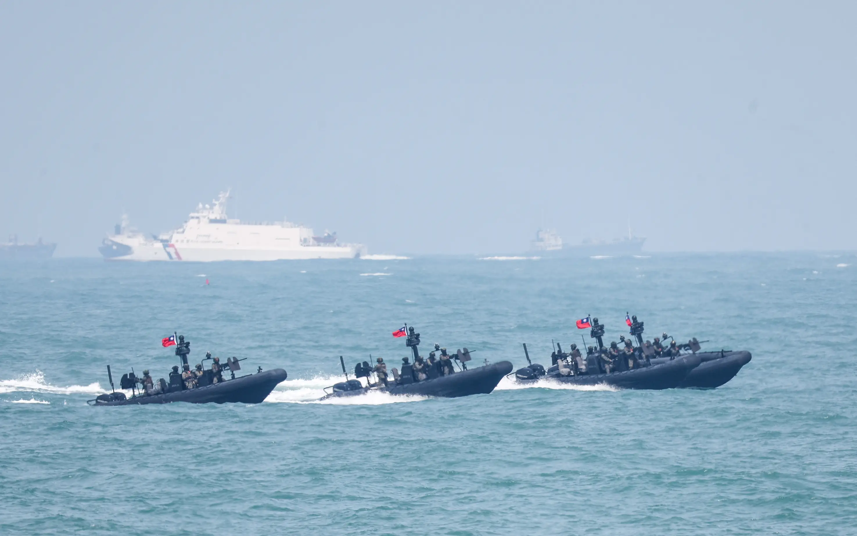 Three M109 assault boats carrying naval special forces speed along the water, while a coast guard frigate watches over the drill.