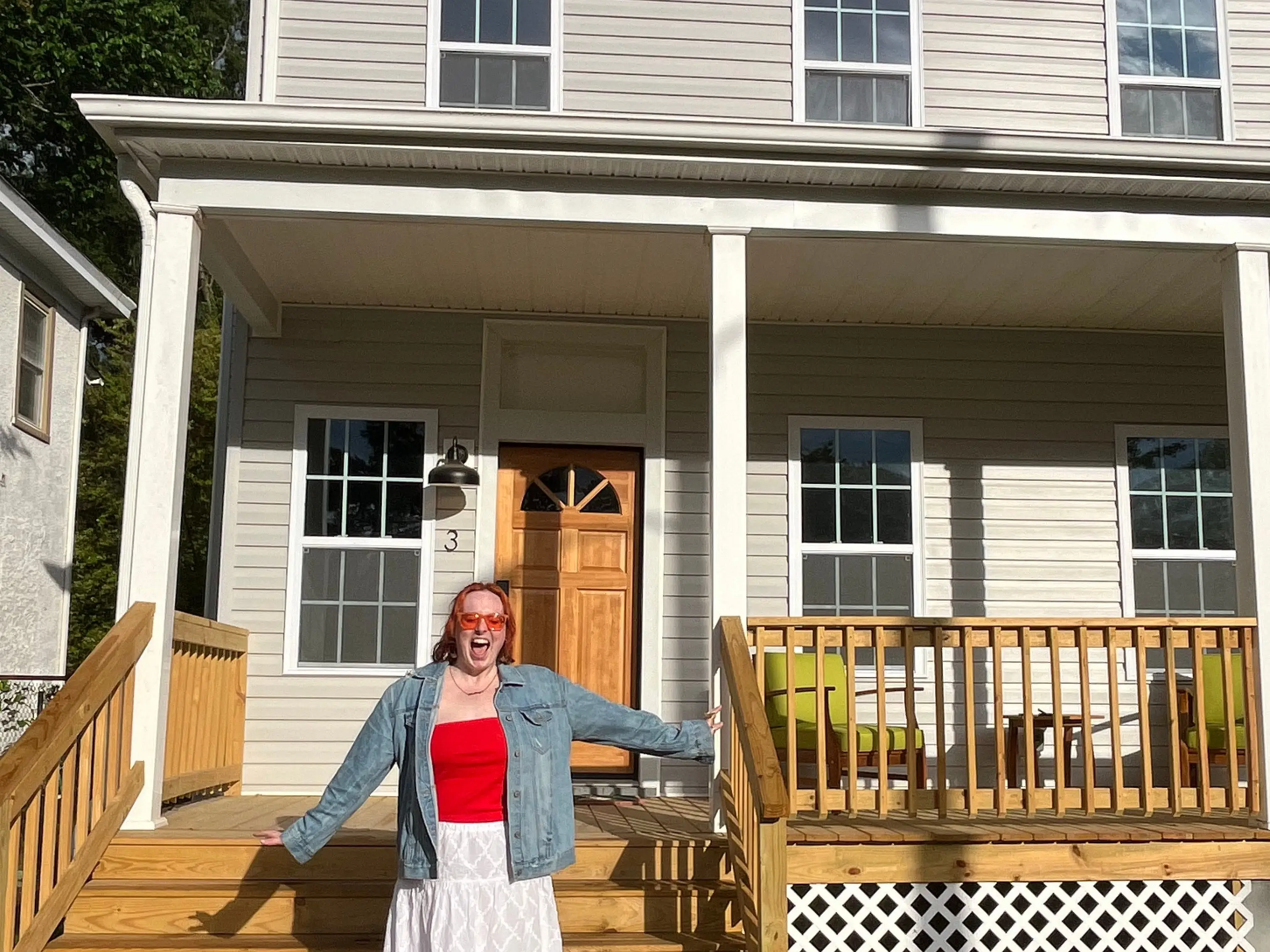 The writer is standing in front of the home she purchased with her mom.
