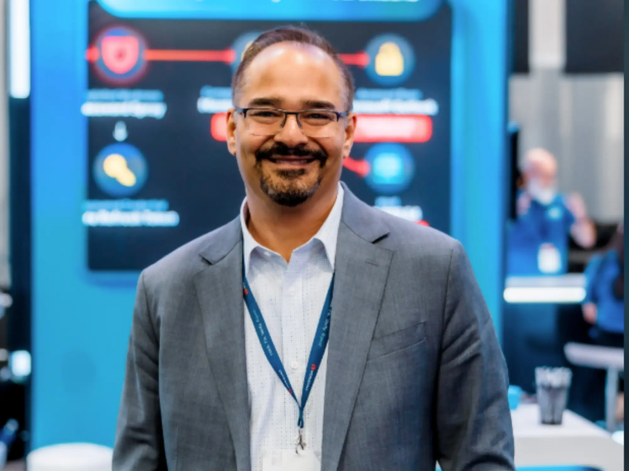 The CEO of Horizon3, an AI hacking startup, smiles. He is wearing a dark blue-gray blazer over a light colored button-down shirt