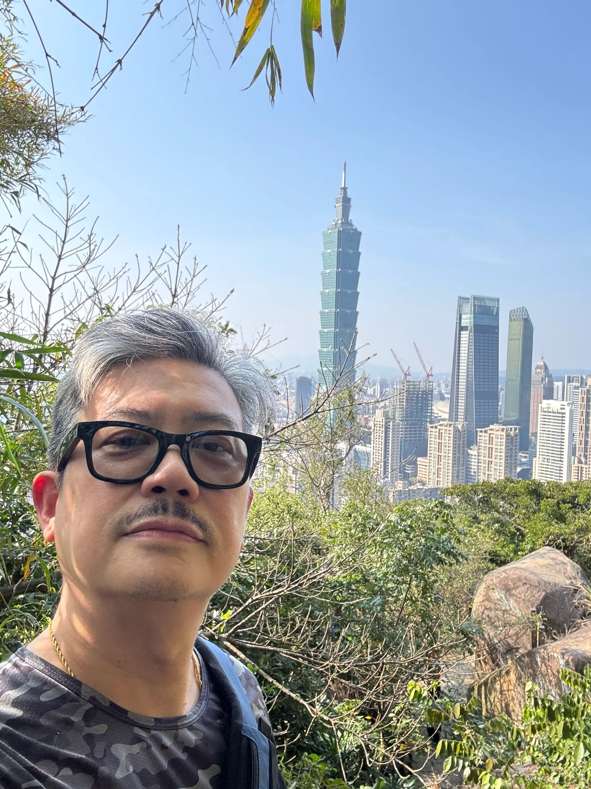 A man taking a selfie in front of the Taipei 101.