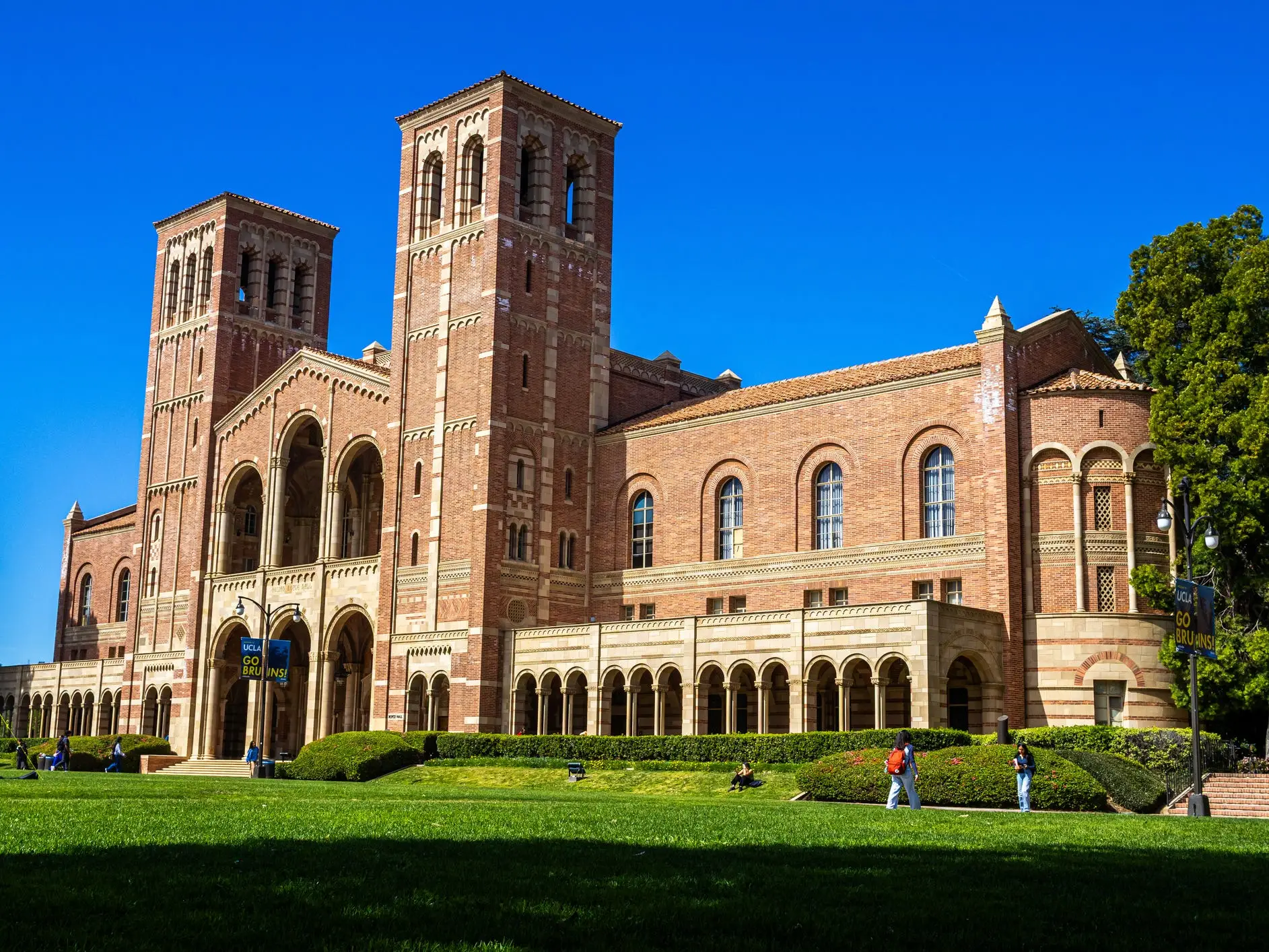 Royce Hall at UCLA stands behind a green campus lawn under a clear blue sky.