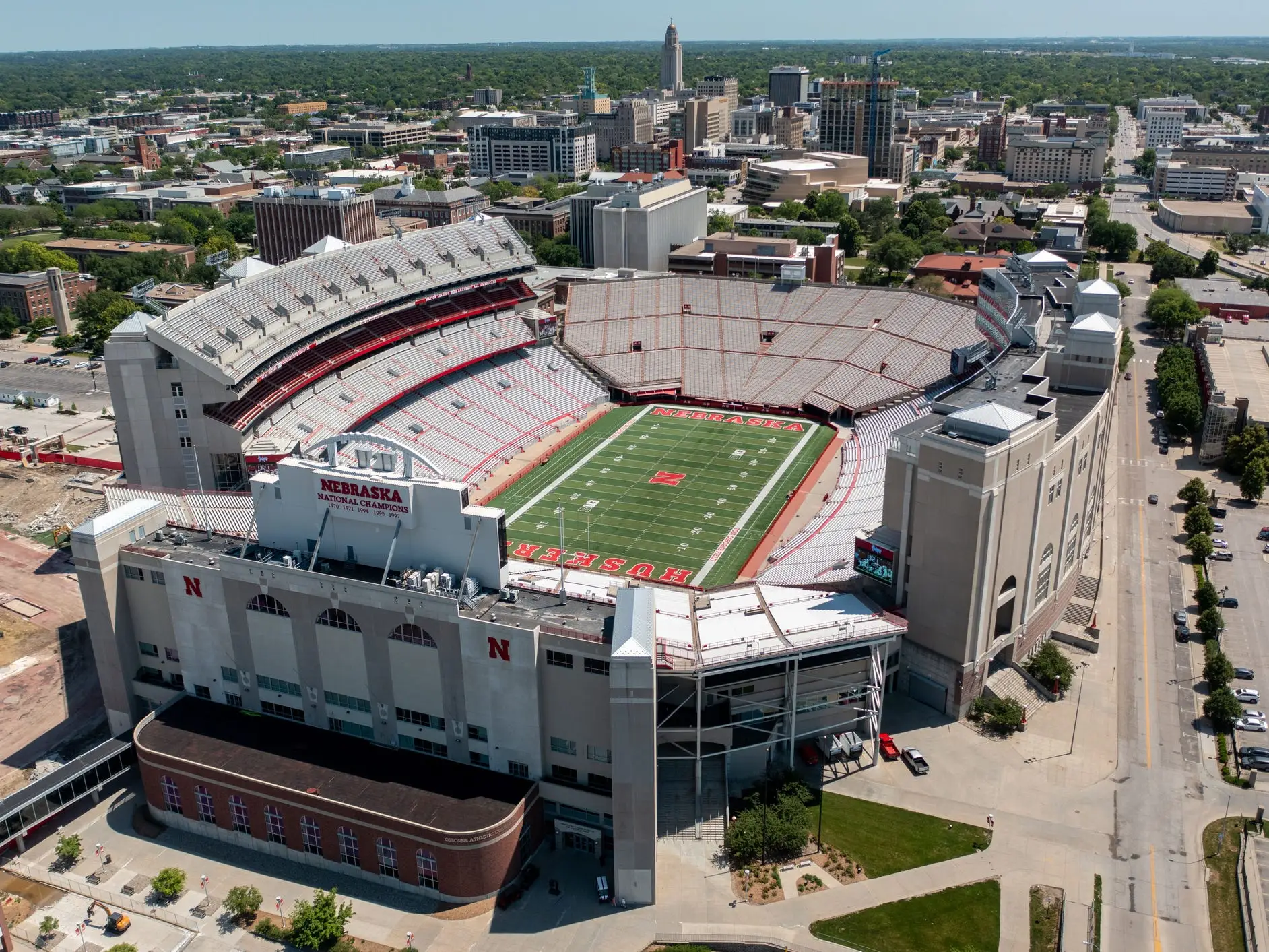 Aerial view of Memorial Stadium with Nebraska football field and surrounding downtown Lincoln buildings.