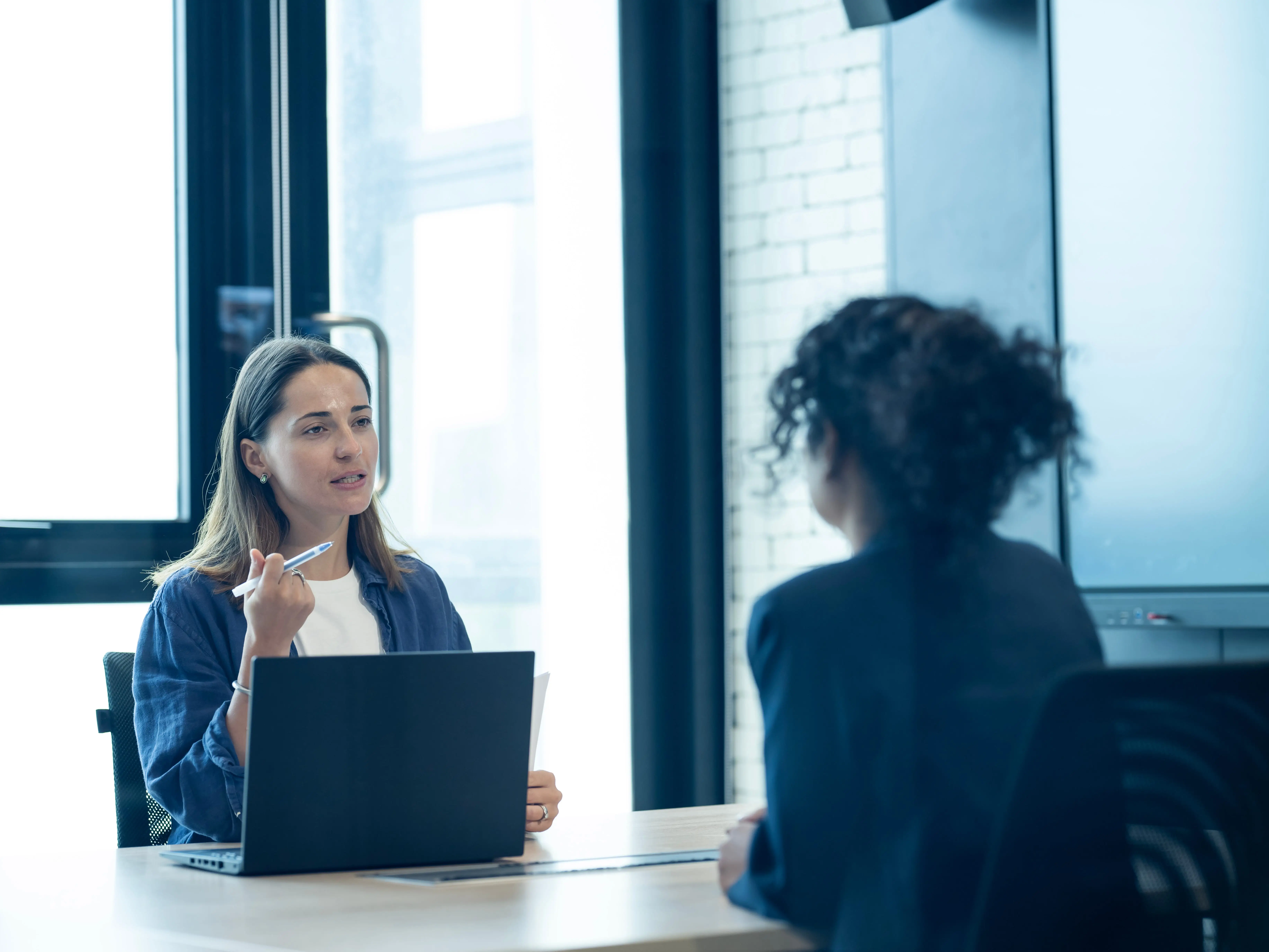 A woman talking to another woman in a workplace setting