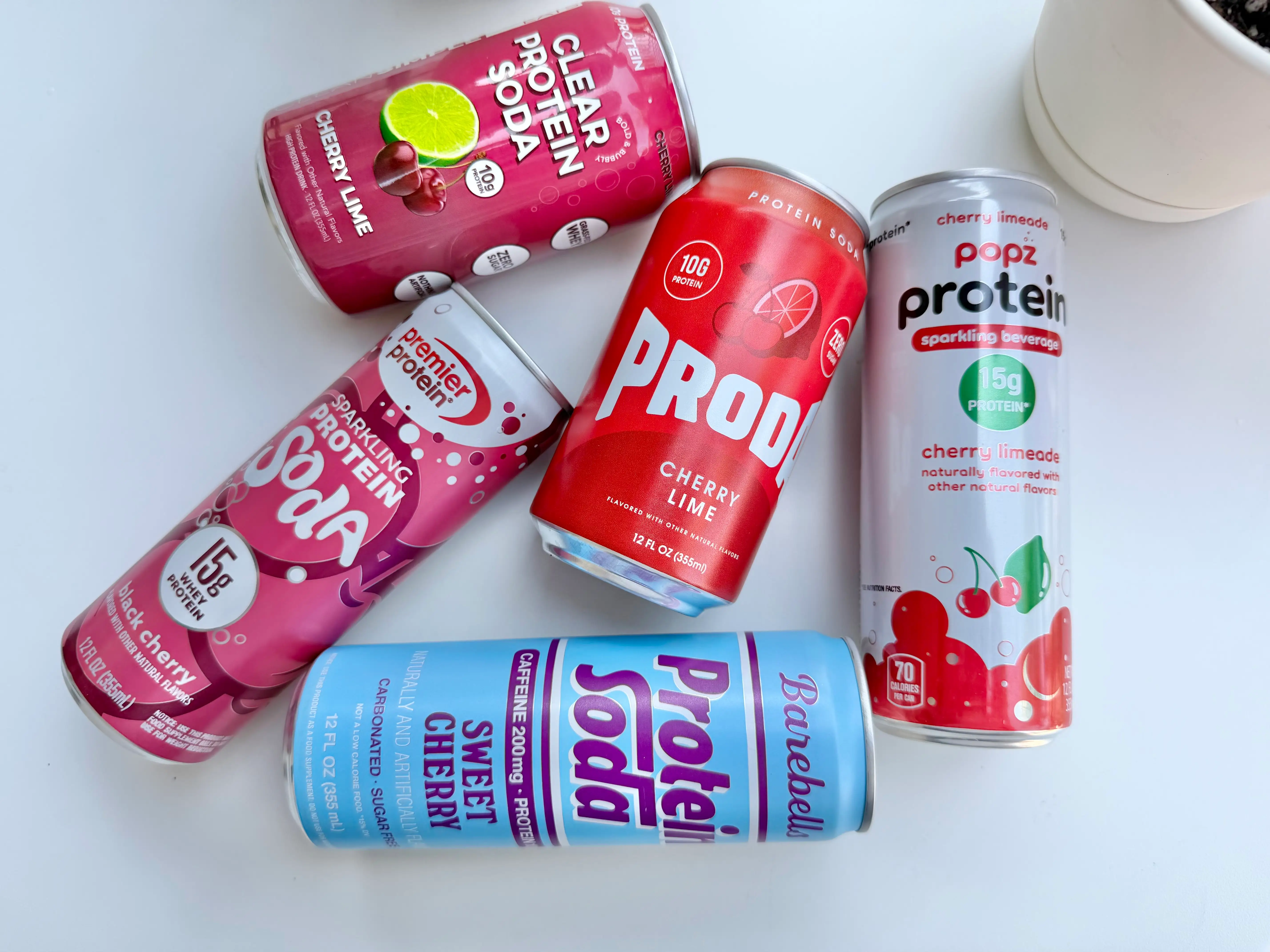 Group of protein soda cans lying on white surface