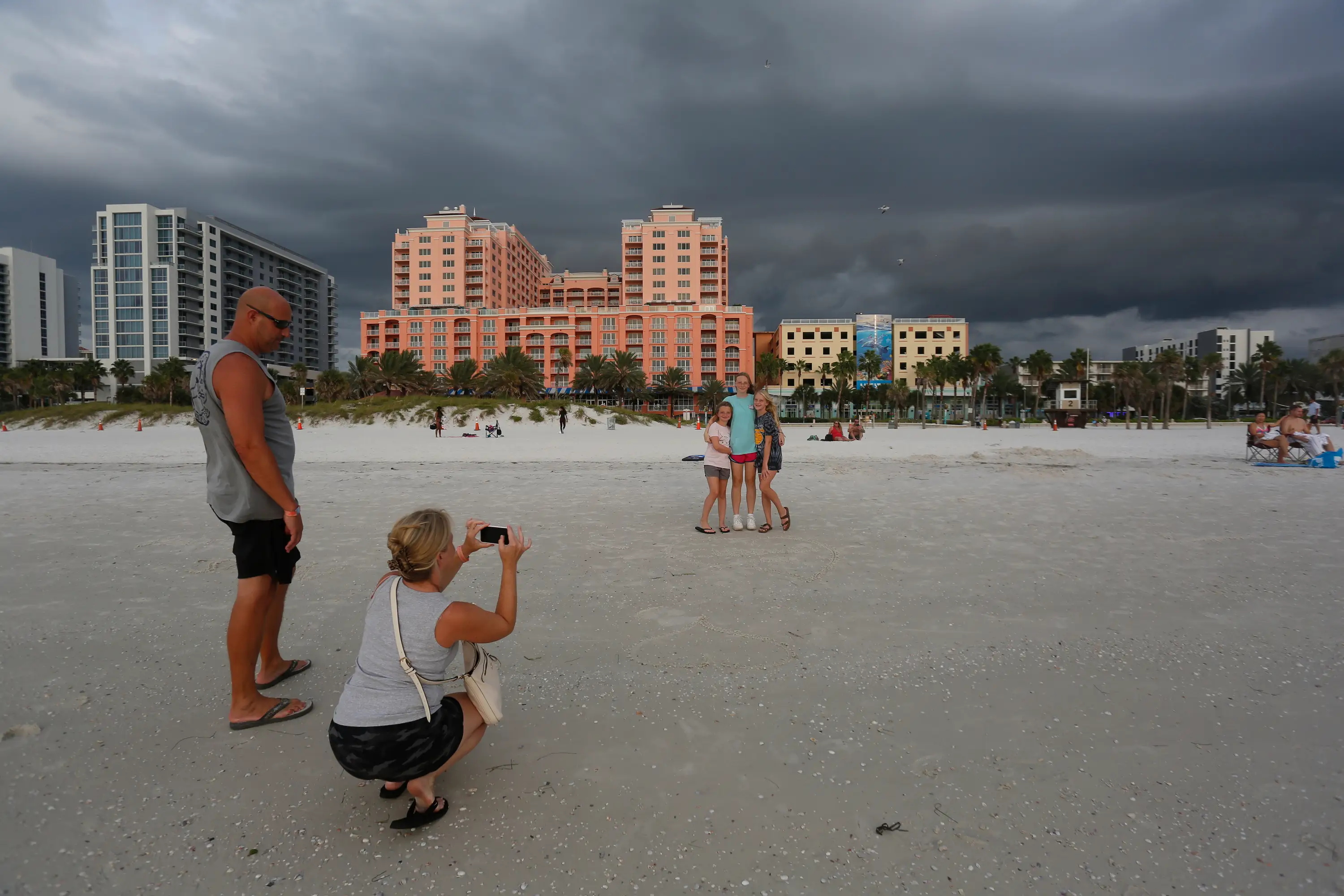 People stand on a beach taking photos.