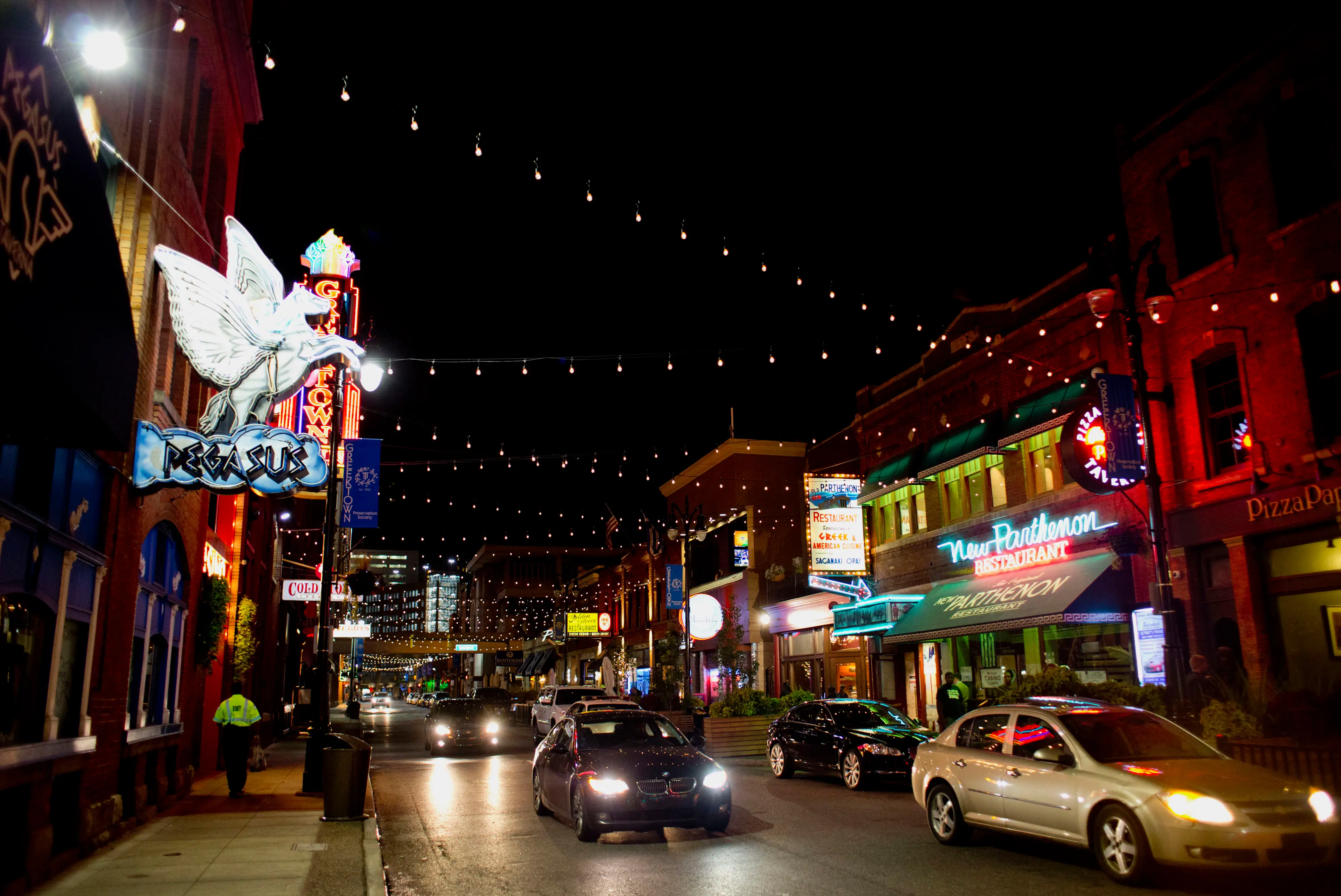 Cars drive through a downtown area at night.