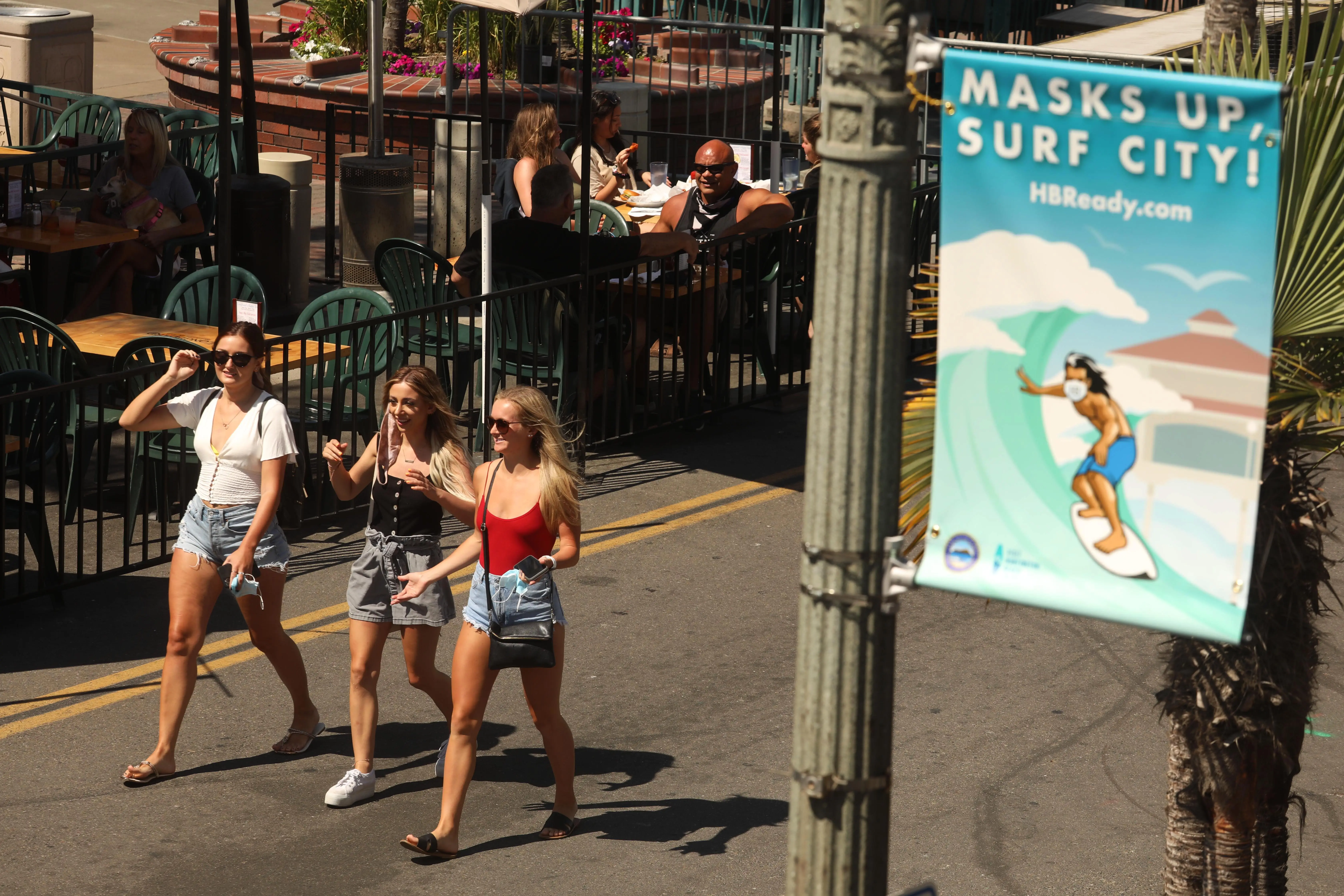 Pedestrians walk on a sidewalk during a sunny day.