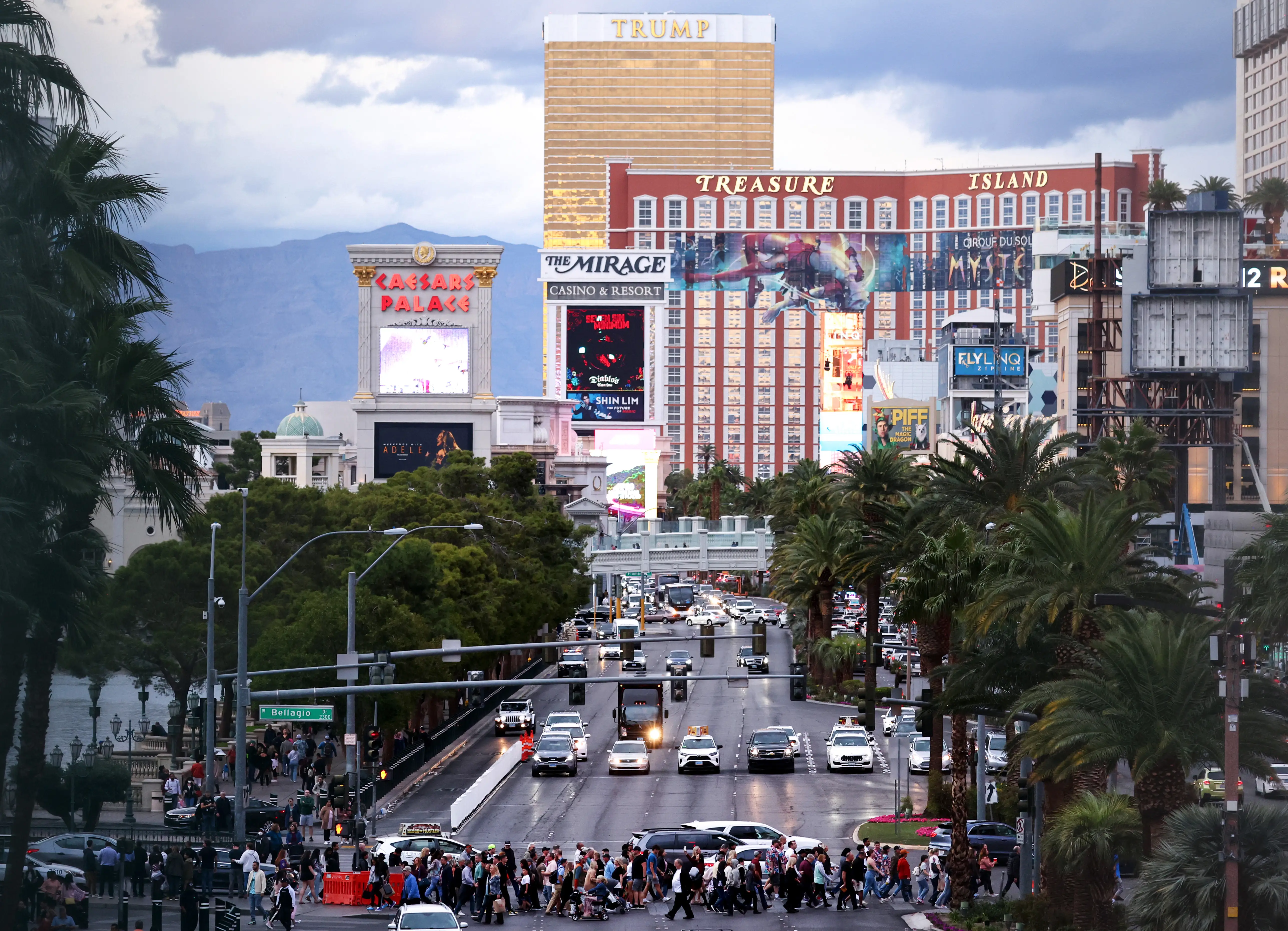 The Las Vegas skyline, with a crowd of people crossing a sidewalk below.