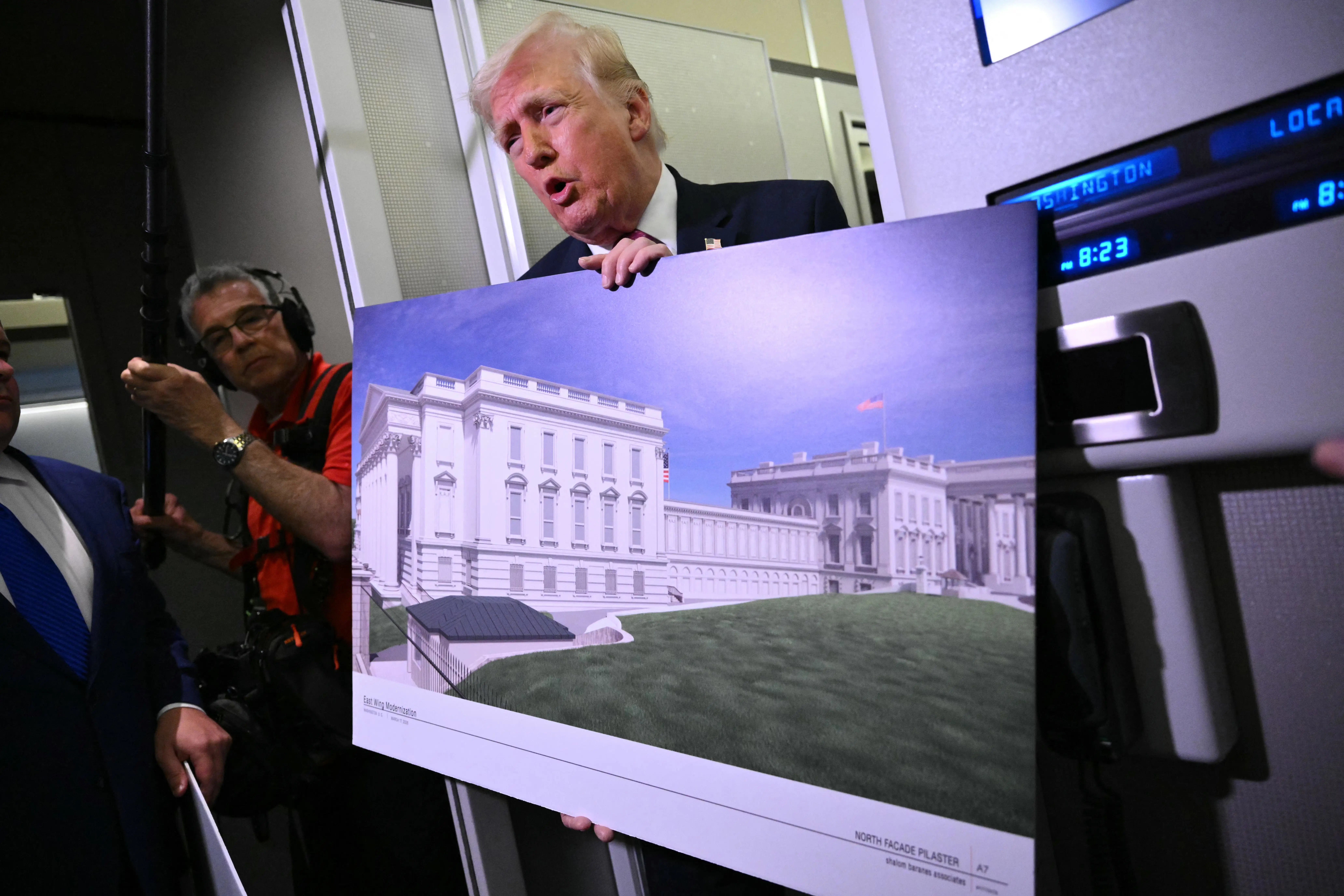 President Donald Trump holds a rendering of the East Wing modernization while speaking to reporters aboard Air Force One.