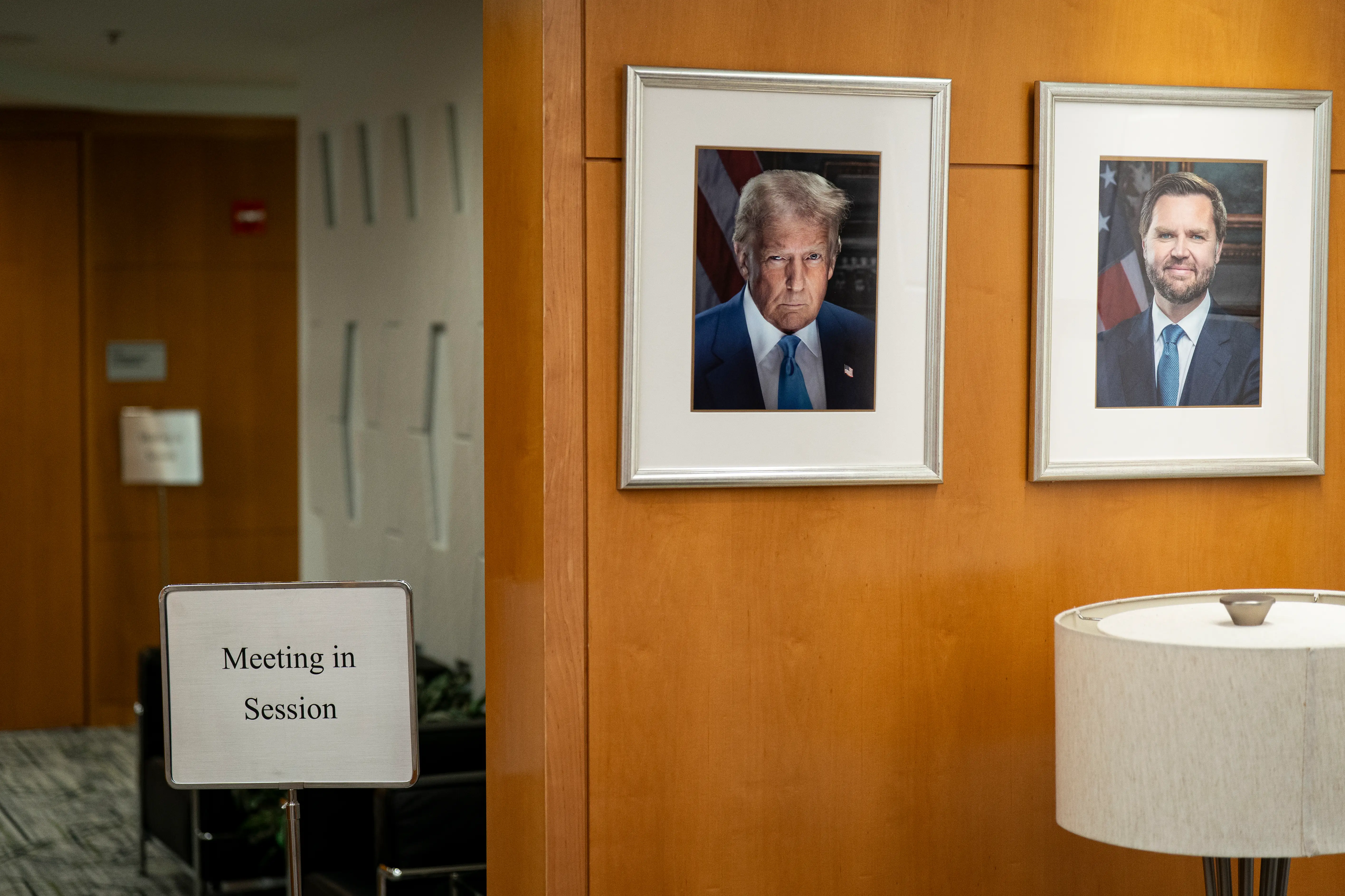 Official portraits of President Donald Trump and Vice President JD Vance on the wall outside a National Capital Planning Commission meeting.