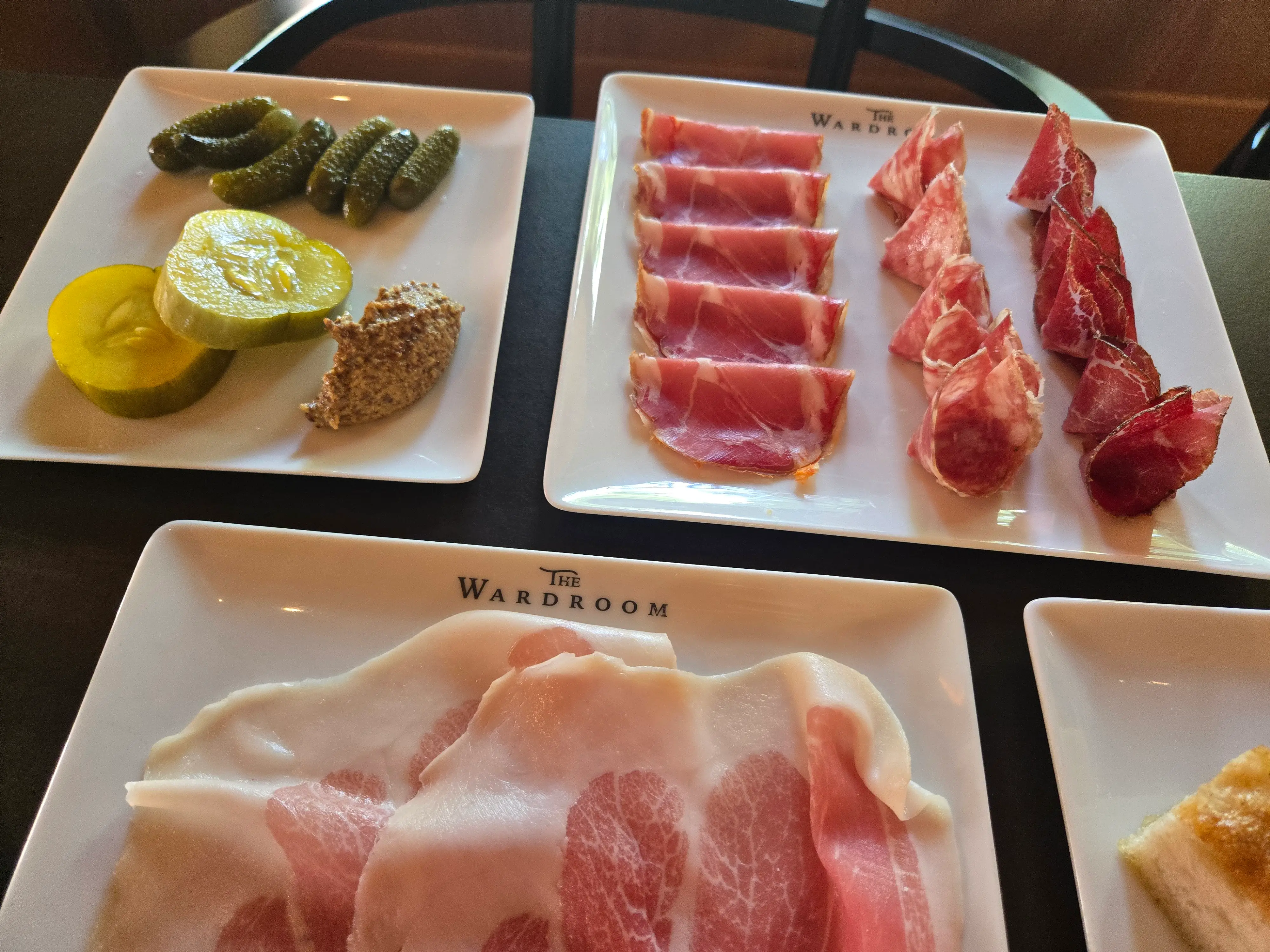 Plates of deli meat and pickles.