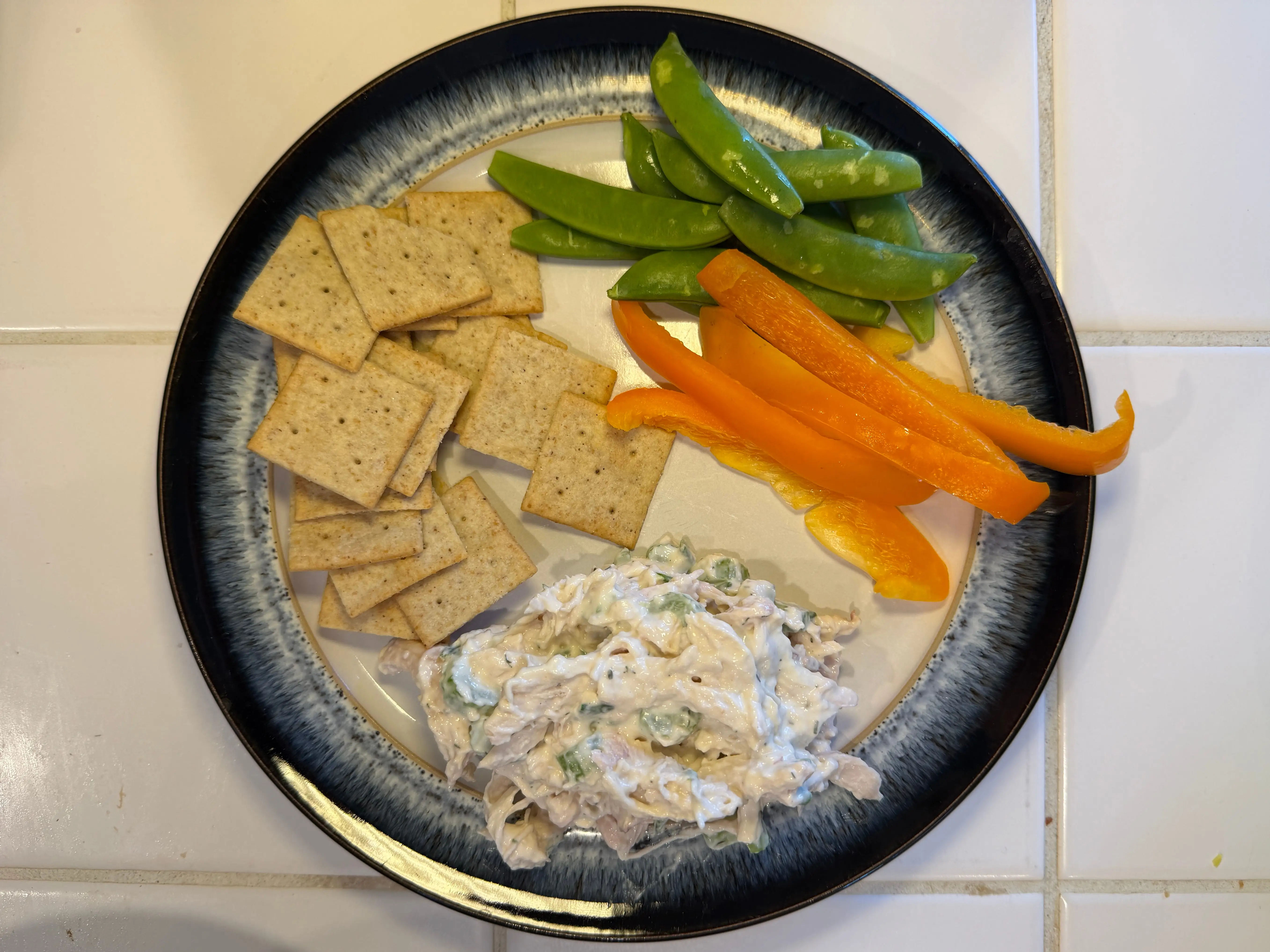 Plate with crackers, chicken salad, sliced bell pepper, and snap peas