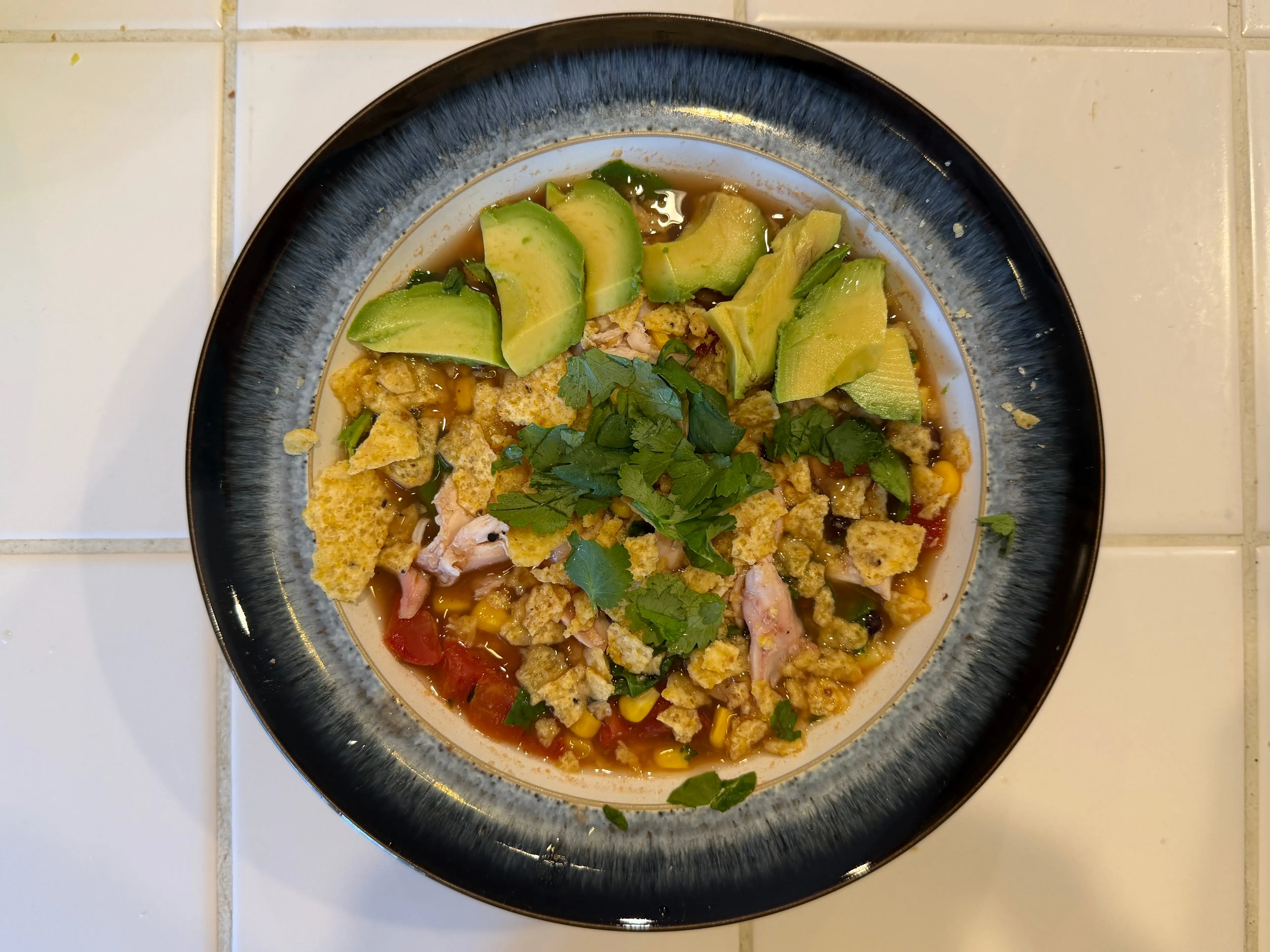 Chicken tortilla soup topped with sliced avocado, cilantro