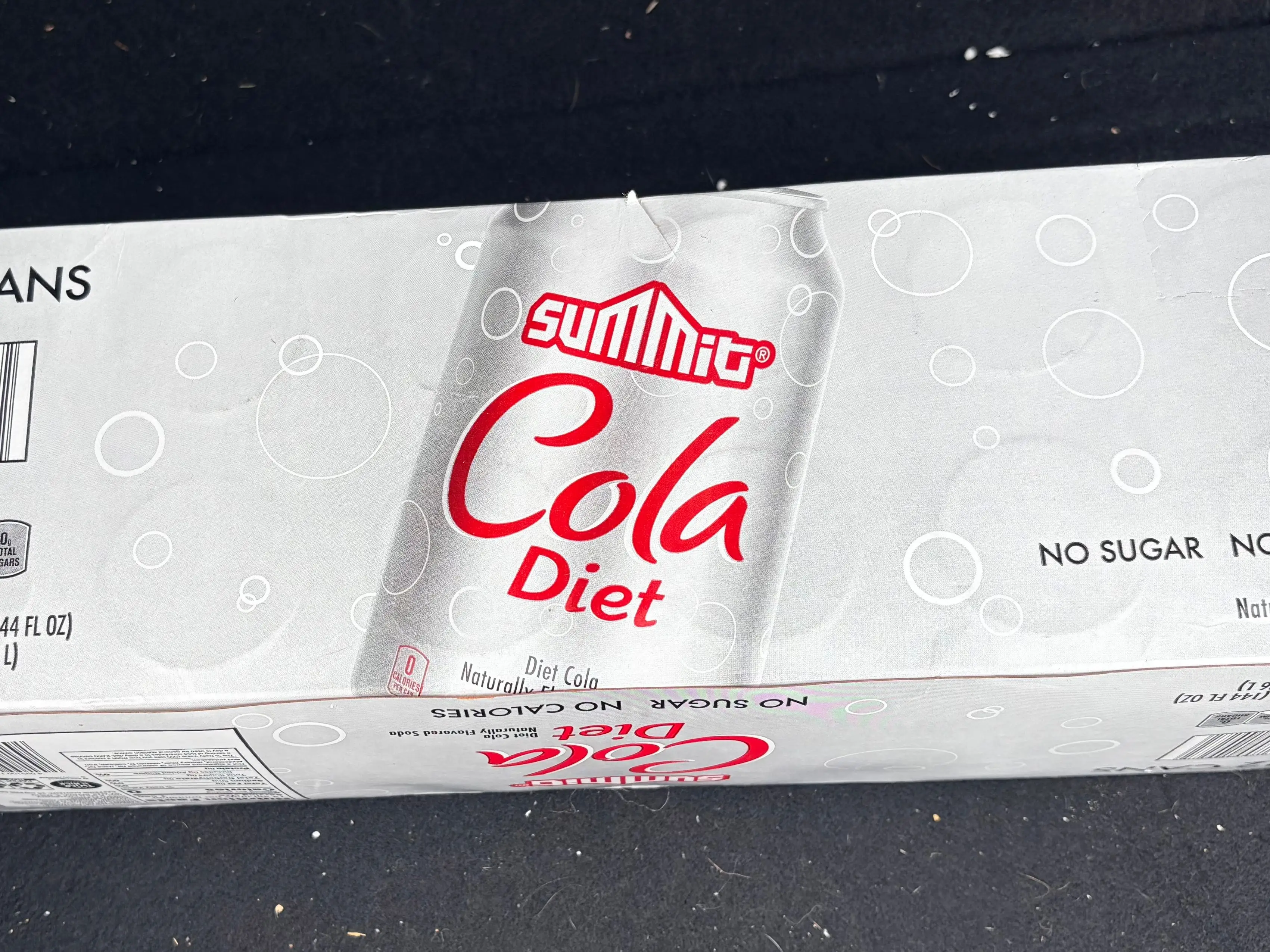 A 12-can box of Summit diet cola rests on a dark fabric surface.
