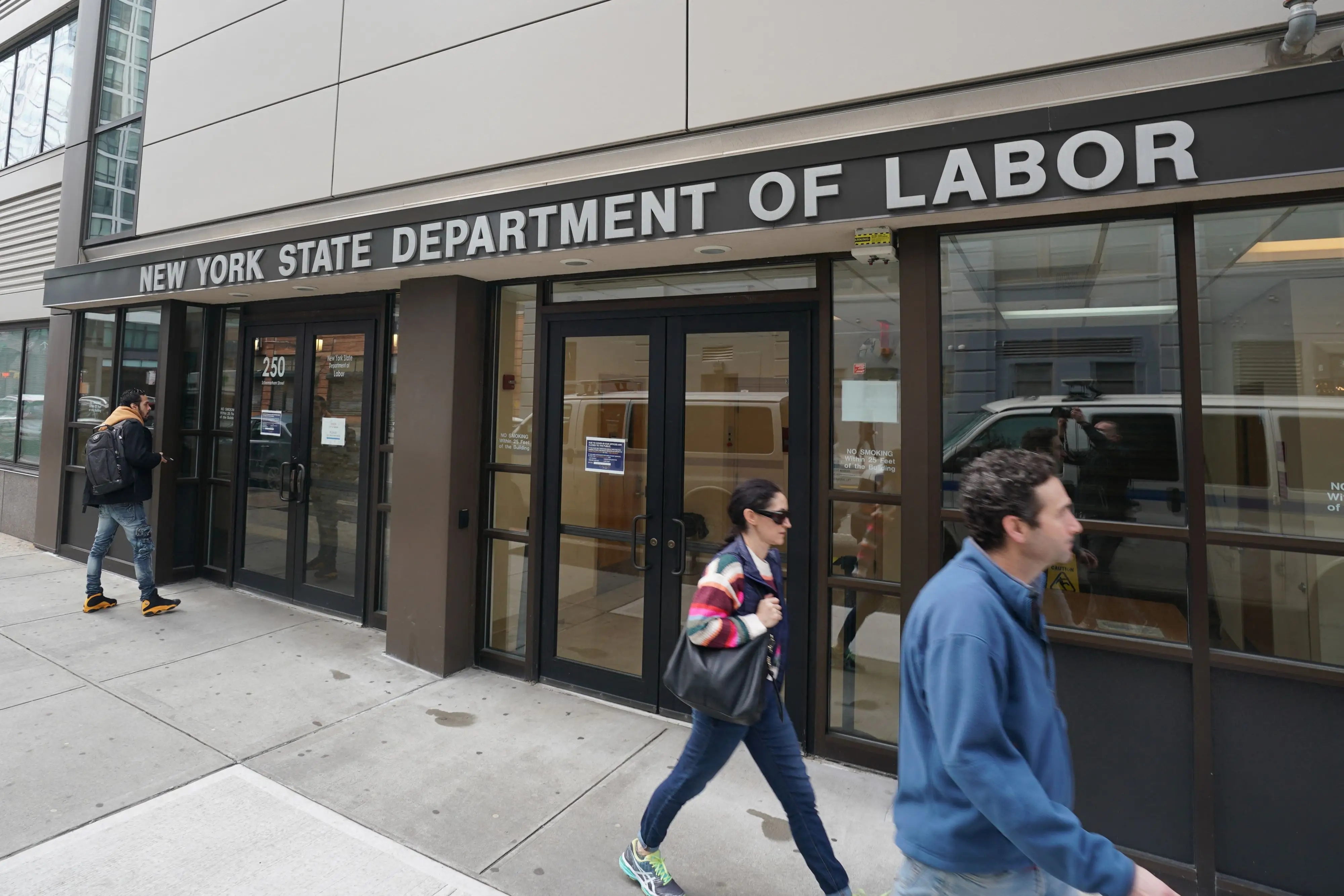 Pedestrians pass the entrance of the New York State Department of Labor.