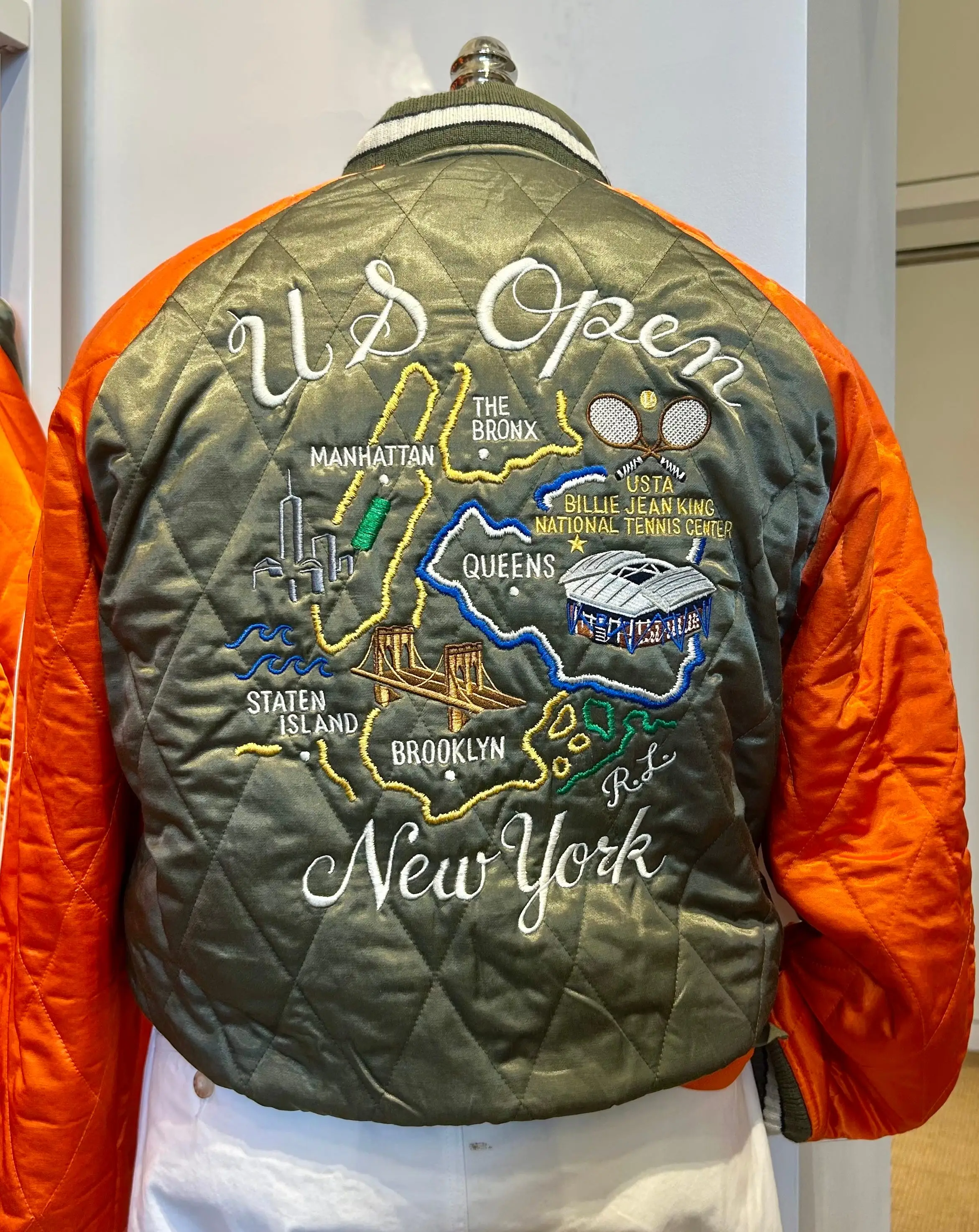 Back of a quilted jacket embroidered with U.S Open New York borough map and tennis center details.