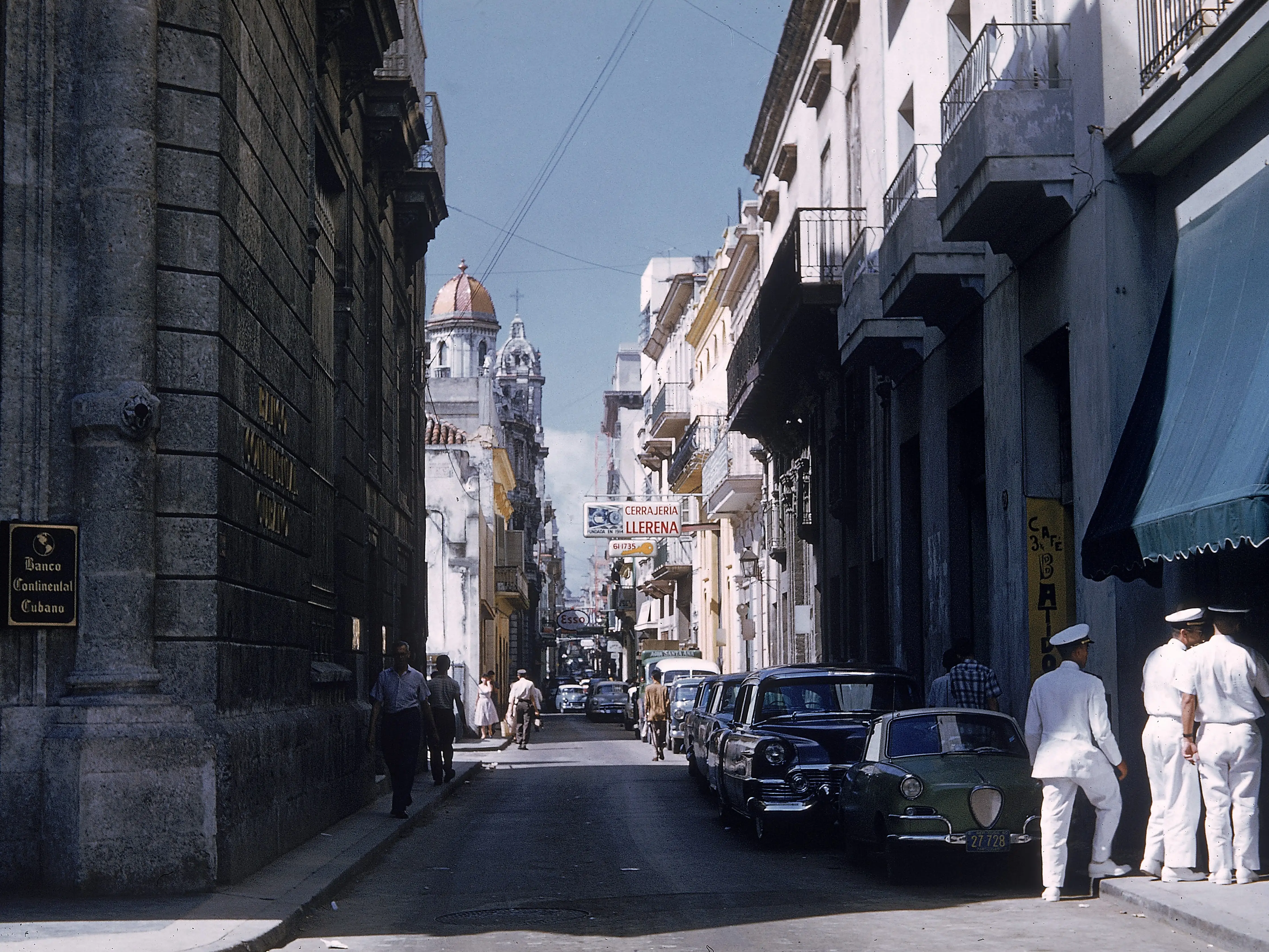 A group of sailors stand outside a cafe at the end of a narrow street in Old Havana, Cuba, 1950s