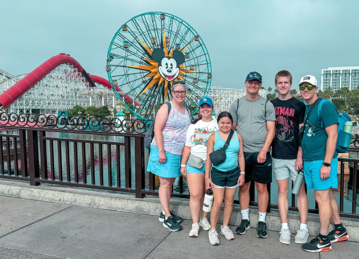 The writer, his wife, his two sons, and two daughters standing in front of a Mickey Mouse Ferris wheel at Disney.