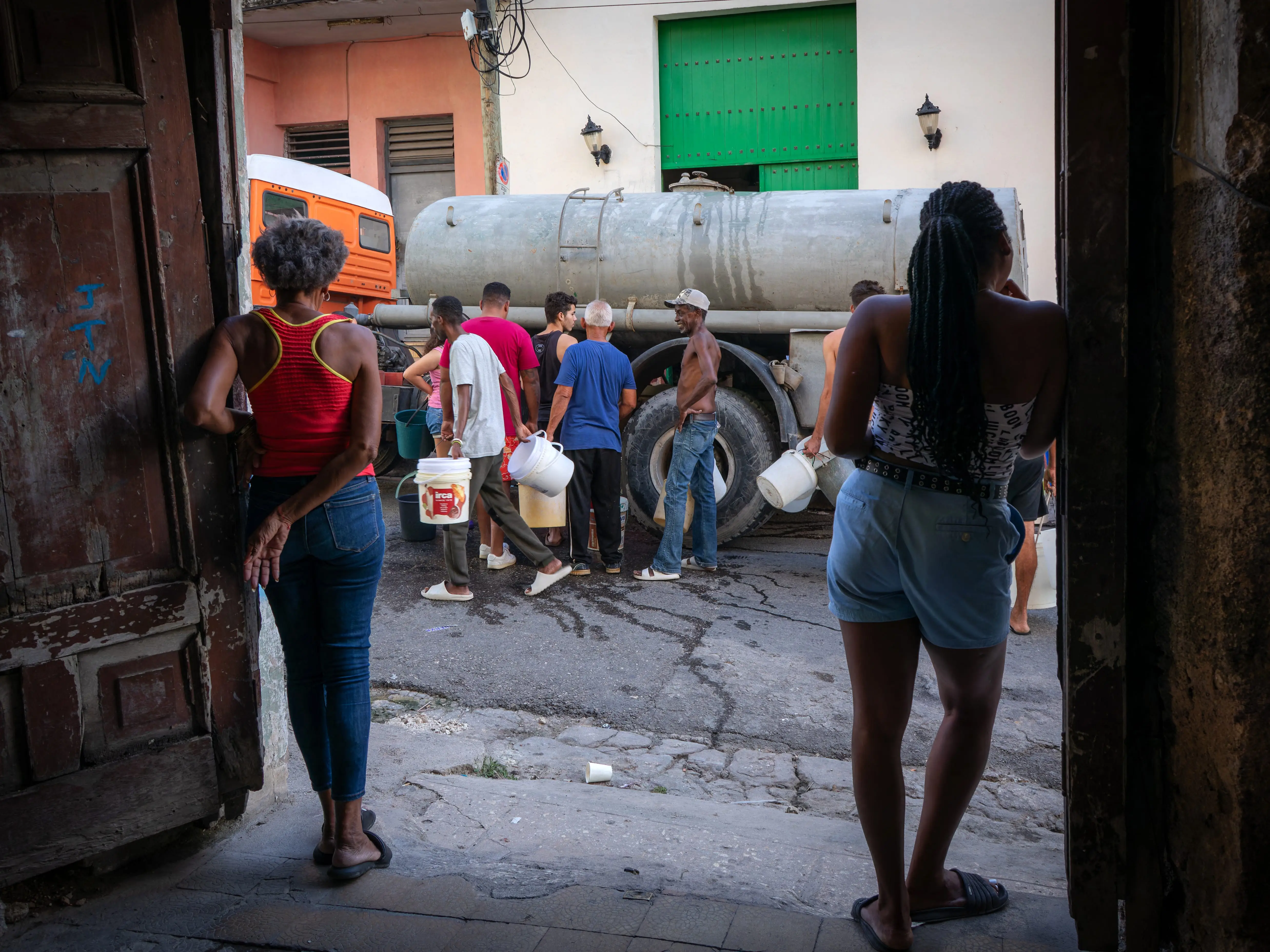 Residents carry containers while queuing for potable water from a water tanker in a neighbourhood of Matanzas, Cuba, on August 6, 2026. Recurring water shortages and power outages have forced many residents of Matanzas to rely on water deliveries and public water distribution points.