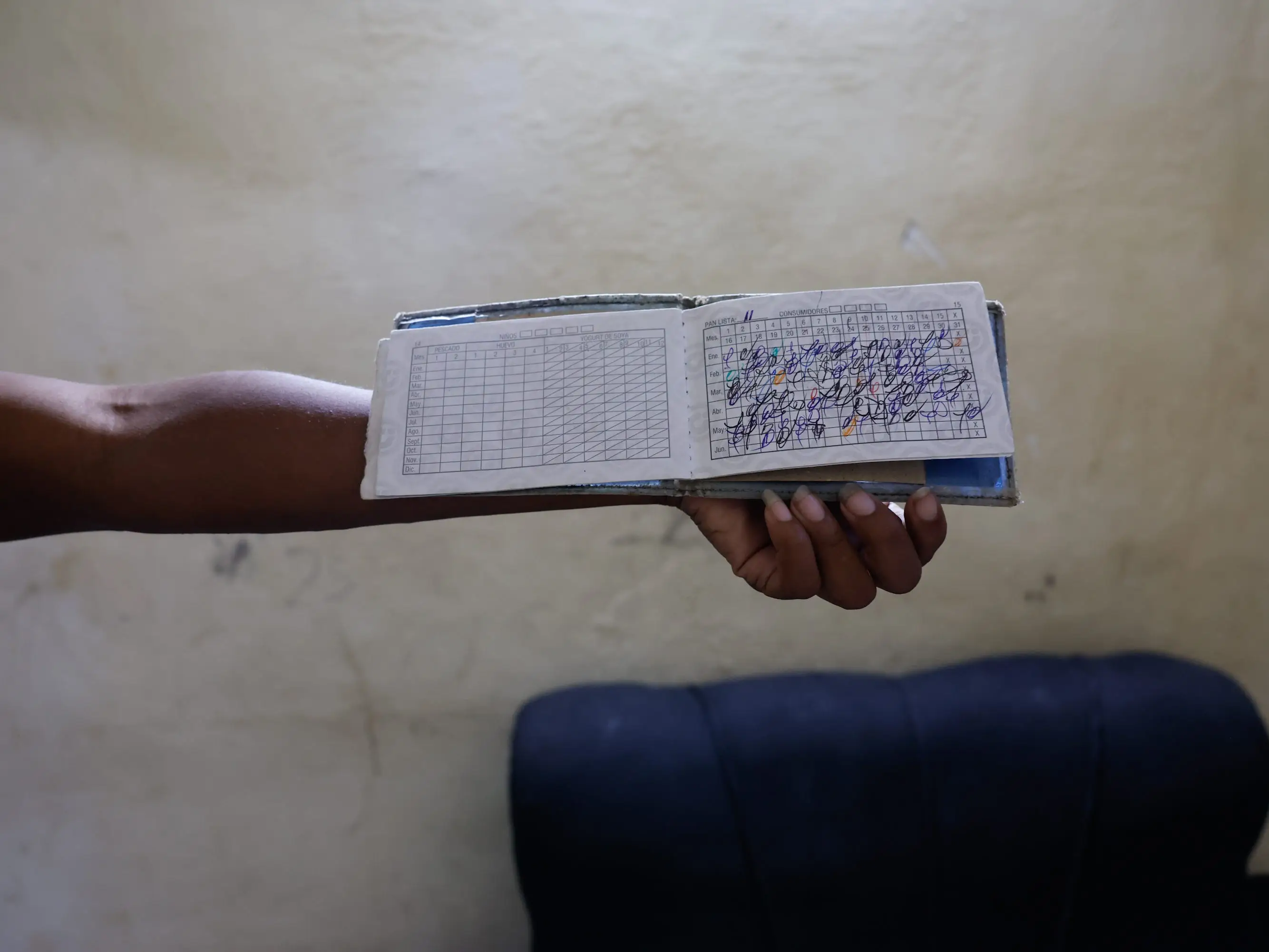 A resident holds up an open 'libreta de abastecimiento' (ration book) used to track subsidized food allocations in Havana, Cuba, on June 09, 2026. Delays in state shipments and severe shortages of staples like rice, beans, and milk have drastically weakened the decades-old rationing system, forcing people to rely on expensive private markets.
