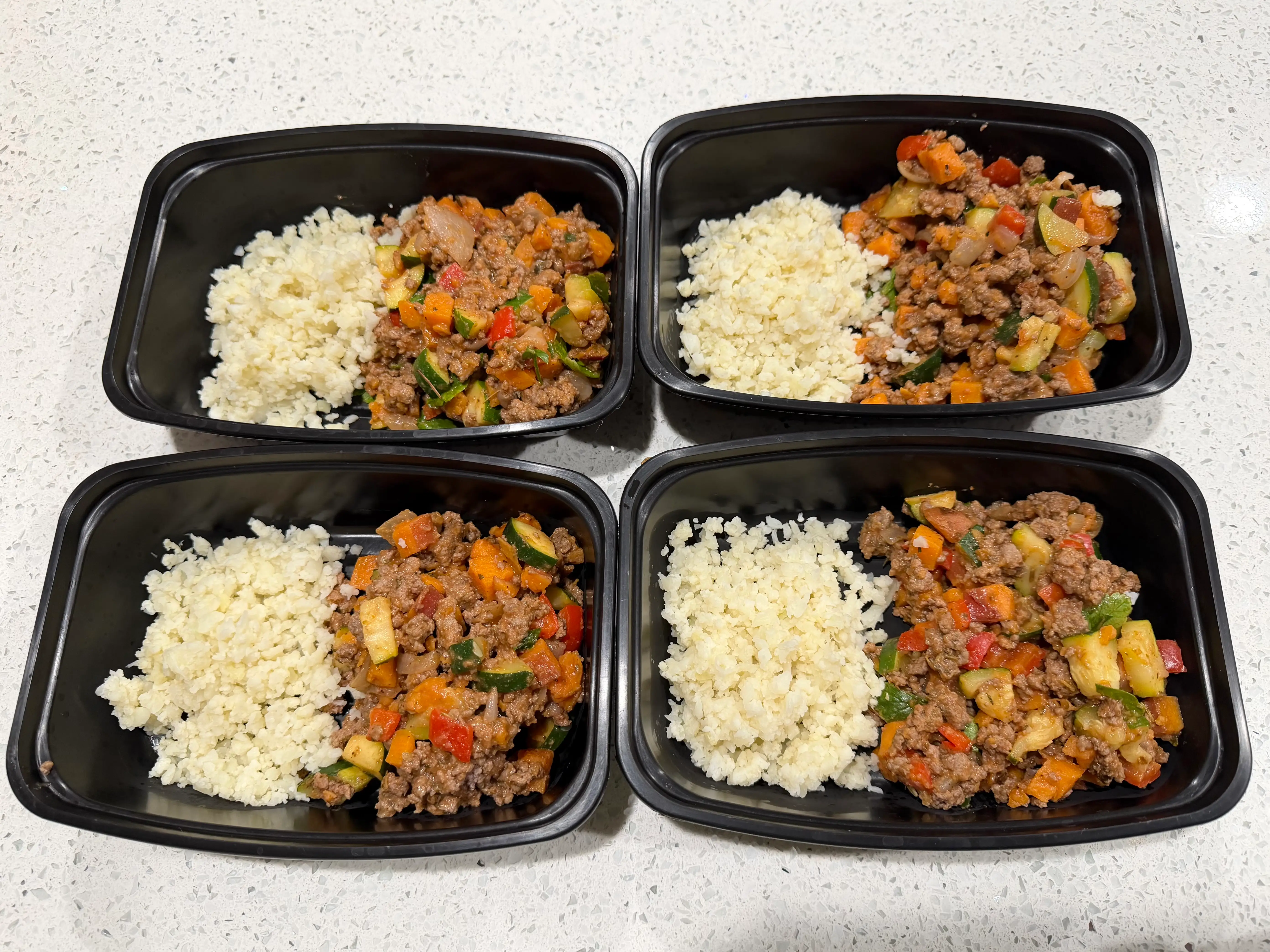 Meal prep containers of cauliflower rice, ground beef, veggies