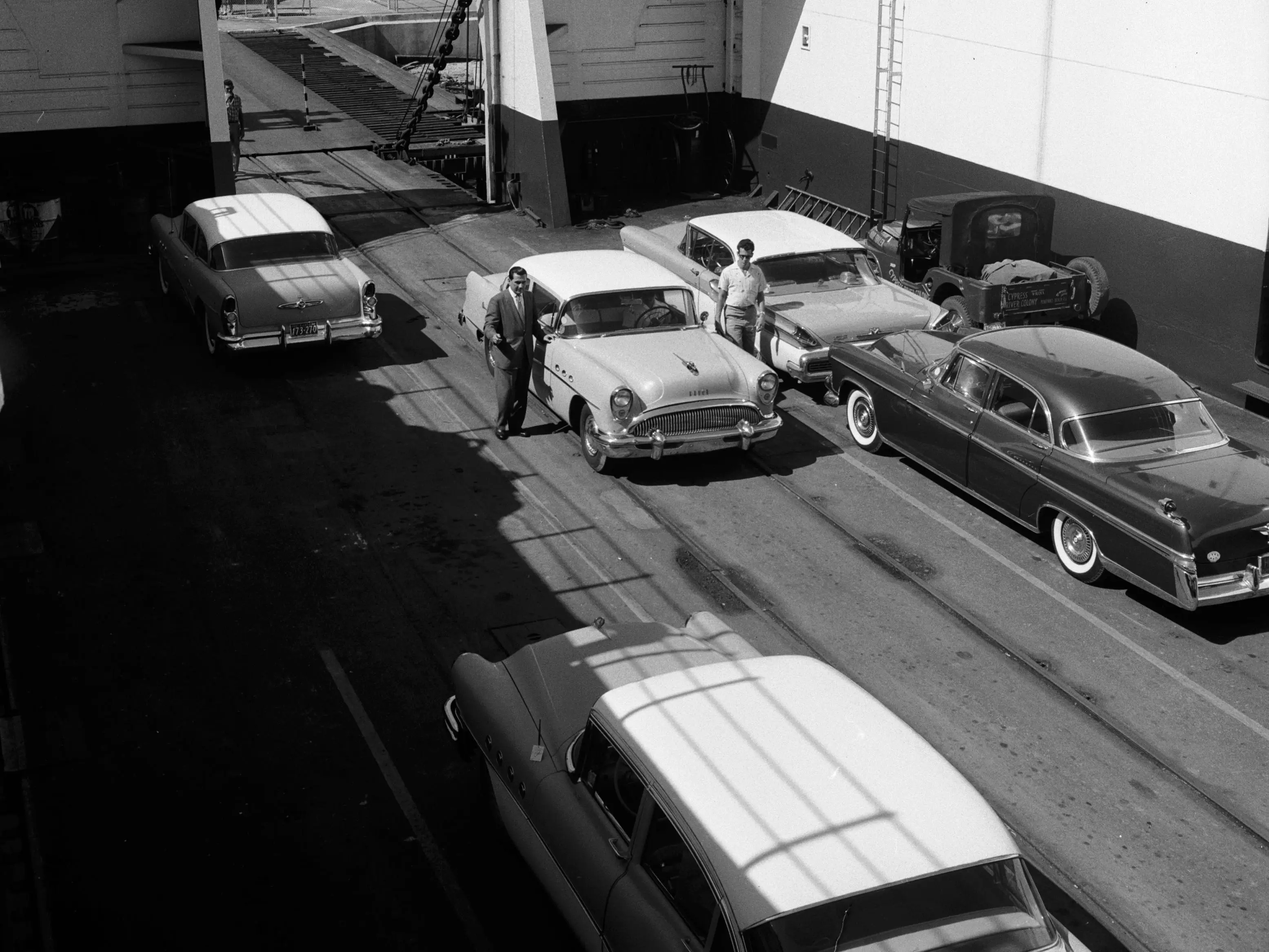 circa 1955: Cuban car importer Celestino Gondar supervising the unloading of American cars from a ferry in Havana harbour.