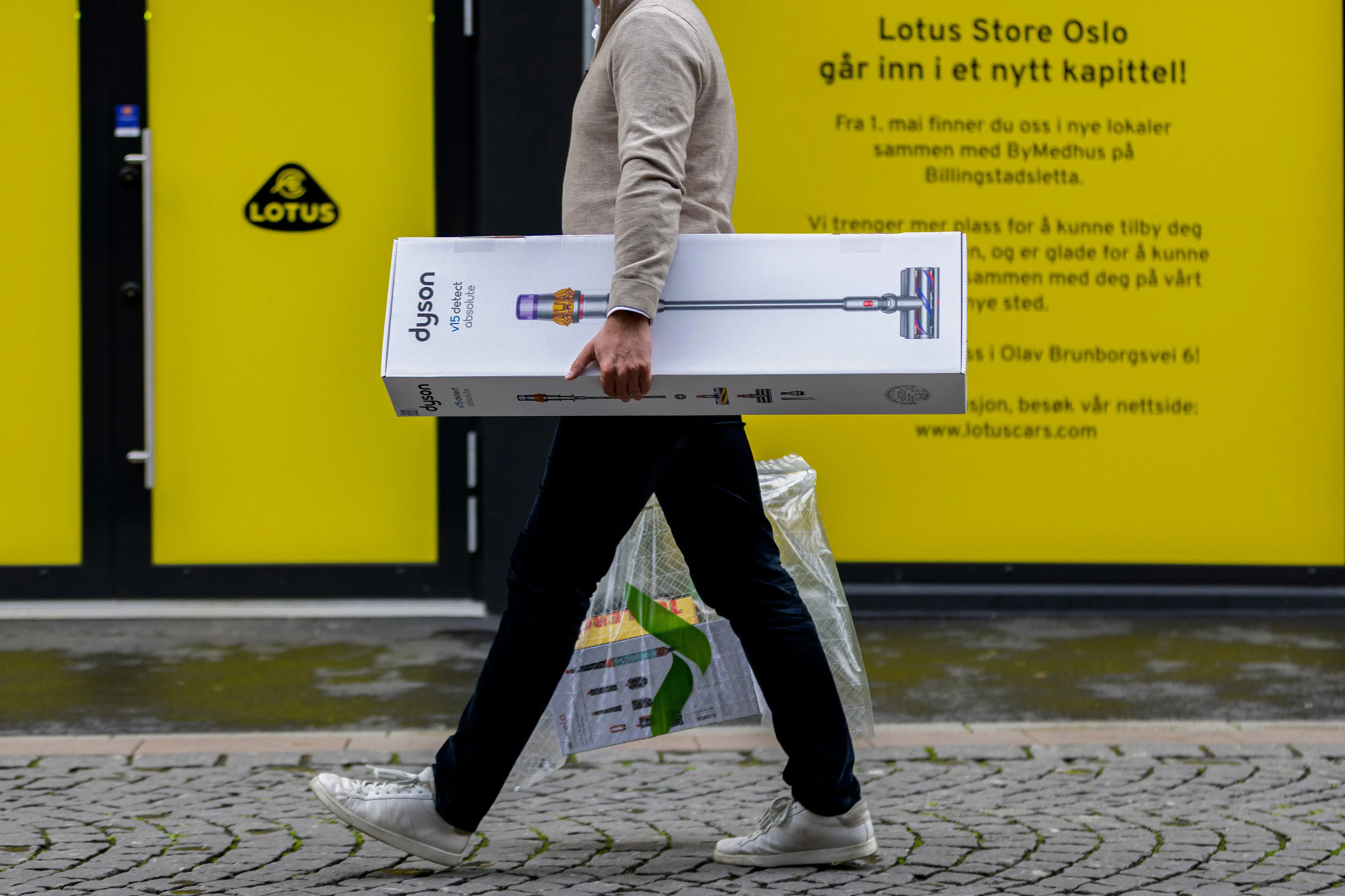 A customer carries a Dyson vacuum box away from a store.