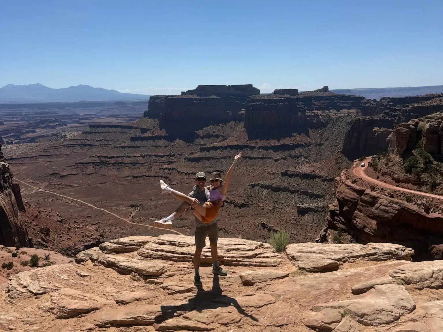 Woman with arms in air smiling in front of rock formations, scenery