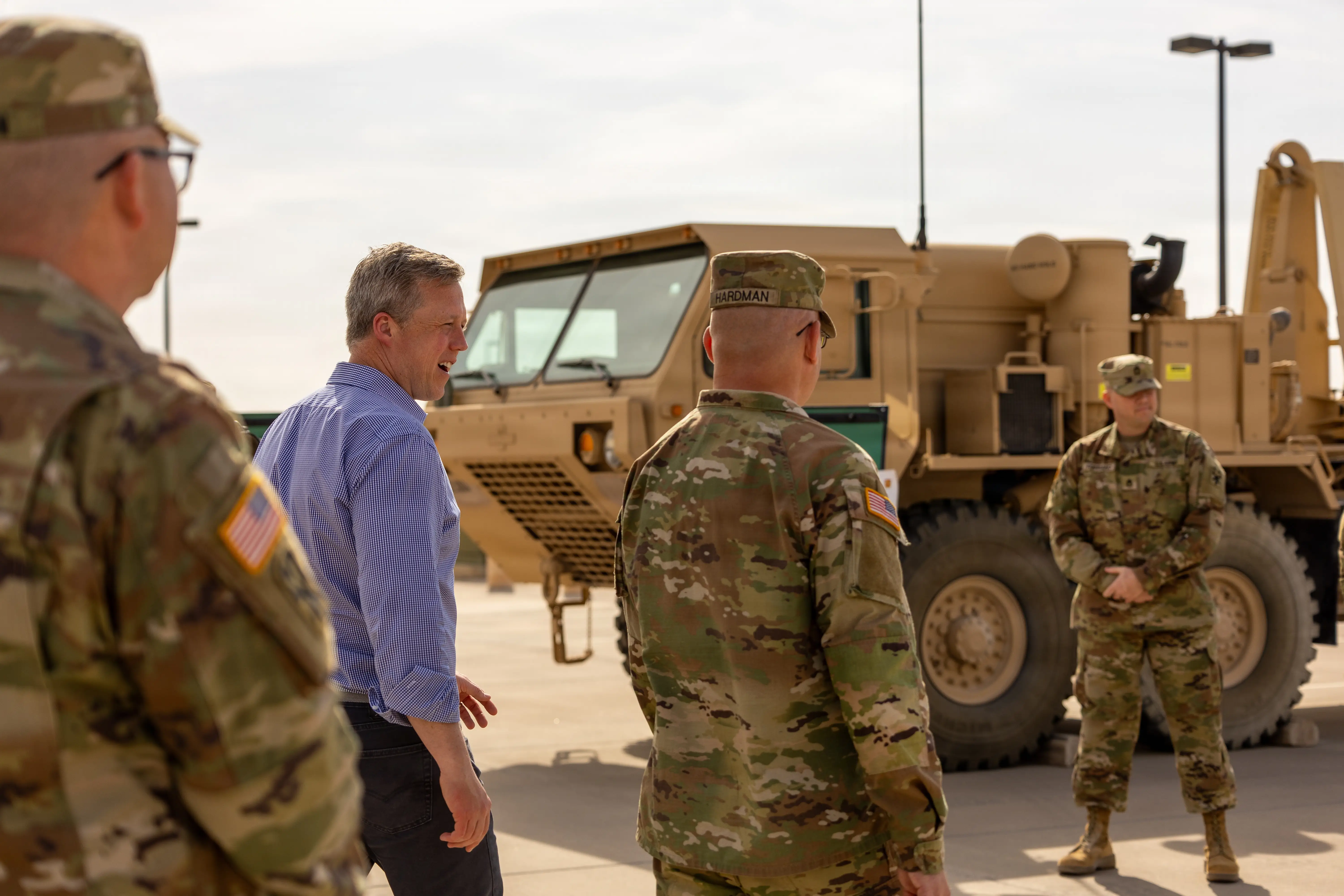 US Secretary of the Army Dan Driscoll walks with US Army soldiers along parked vehicles.