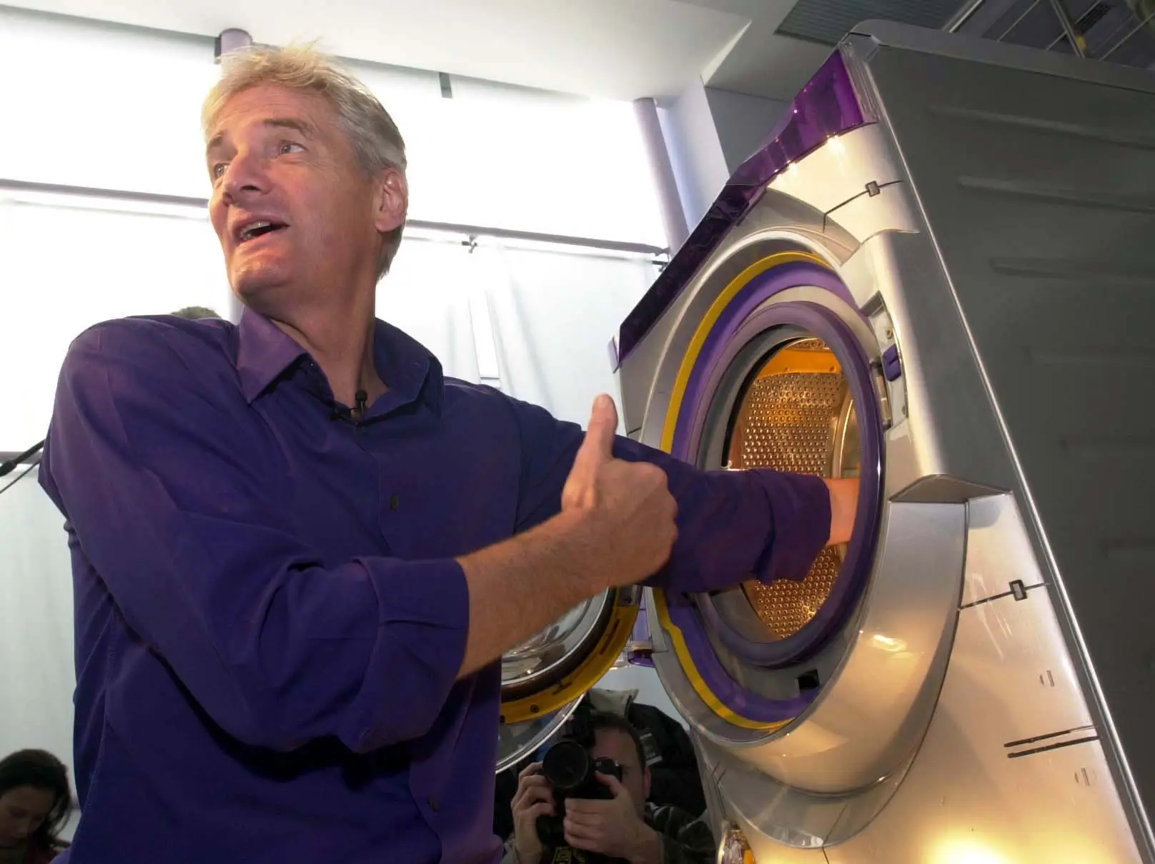 Inventor James Dyson sticks his hand into a Dyson washing machine.