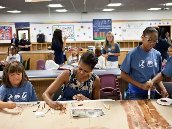 First Lady Michelle Obama works on backdrop props for student theater production of 