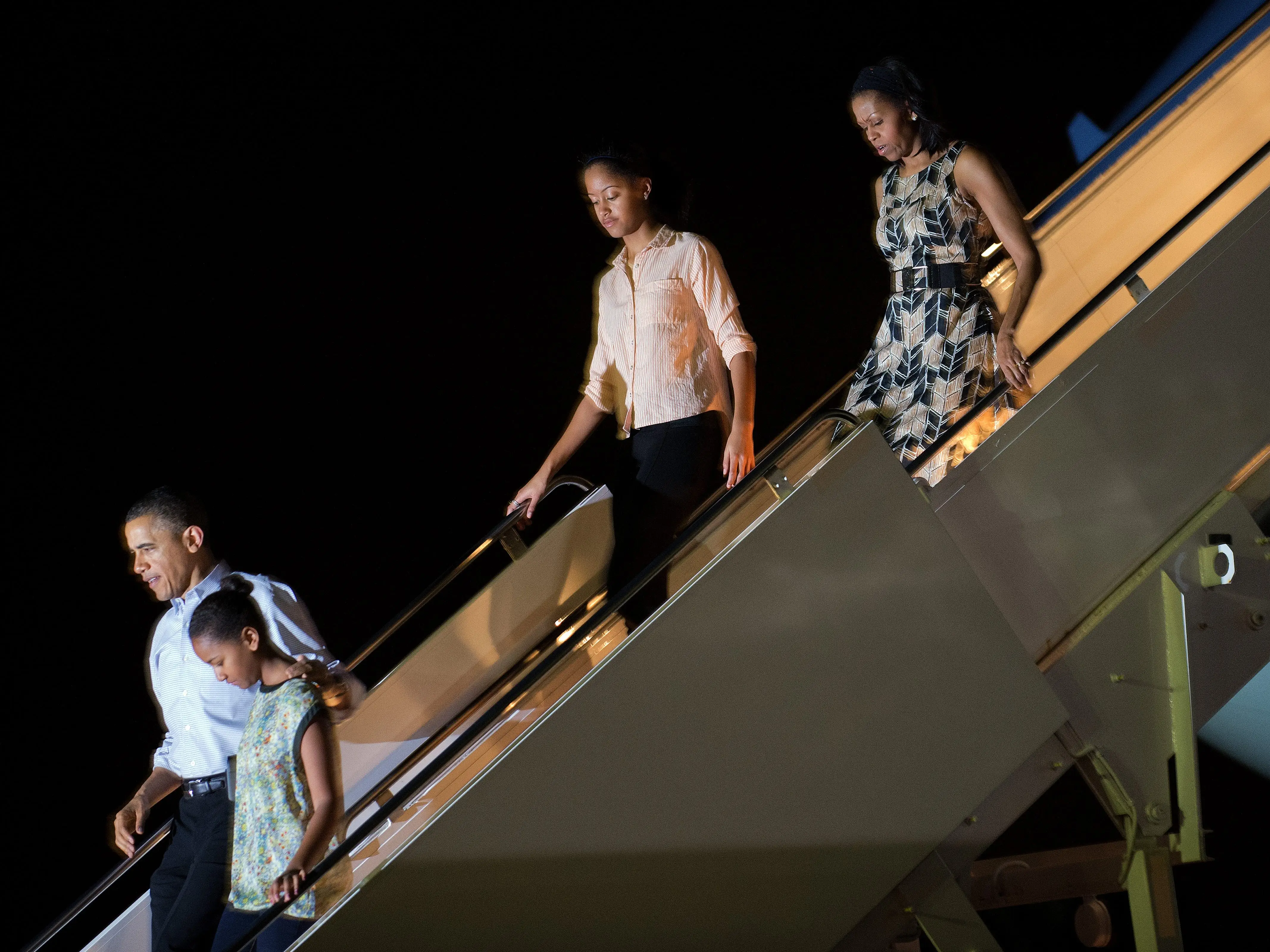 US President Barack Obama (L) walks with his daughters Sasha (2nd L) and Malia (2nd R), as well as First Lady Michelle Obama (R), off Air Force One at Hickham Feild in Honolulu, Hawaii, early on December 22, 2012.