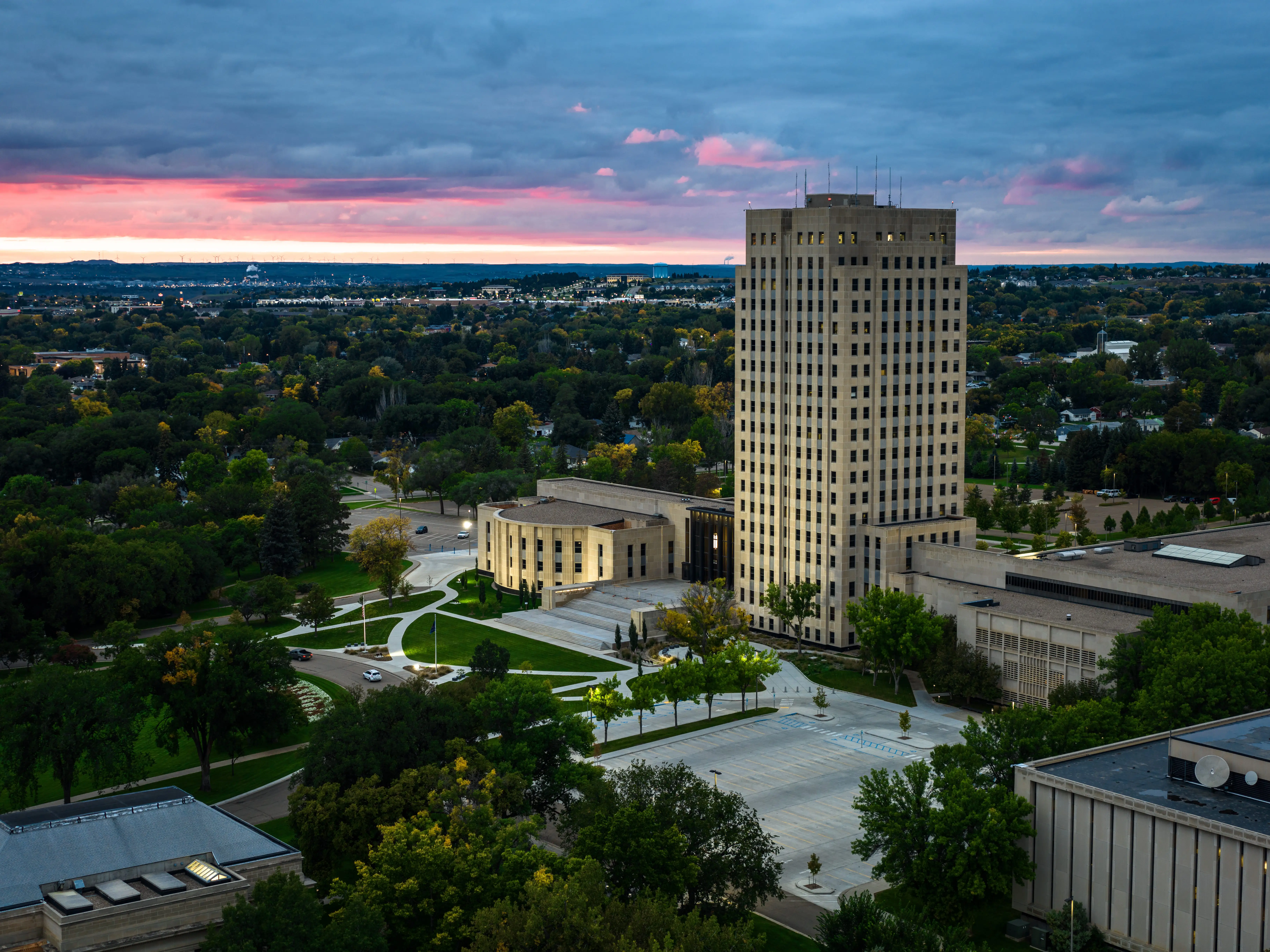 Aerial view of the North Dakota State Capitol in Bismarck, North Dakota, on a dramatic overcast sunset with a red-tinted sky in the fall.
