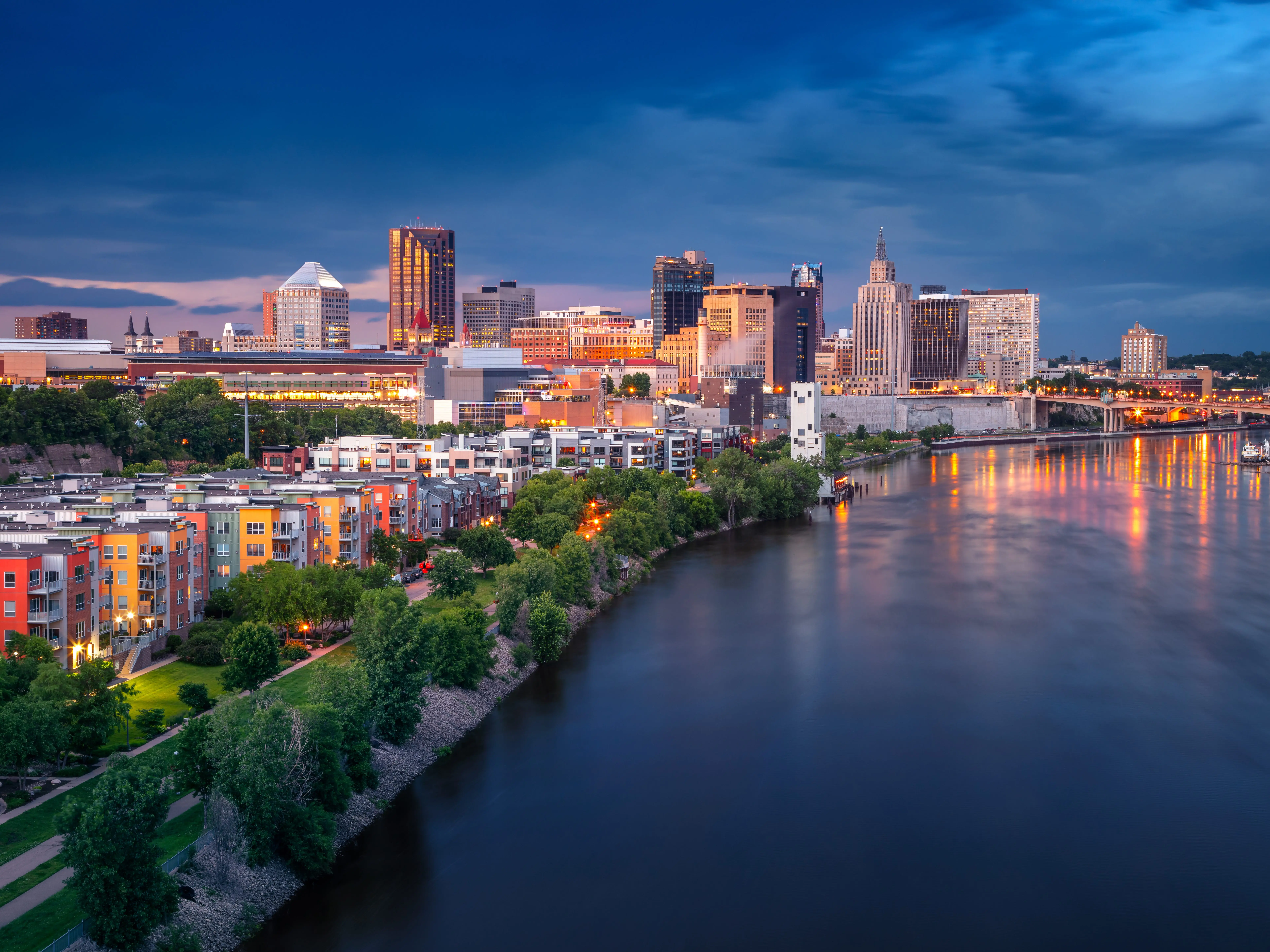 Aerial cityscape image of downtown St. Paul, Minnesota, USA with reflection of the skyline in Mississippi River at stormy summer sunset.
