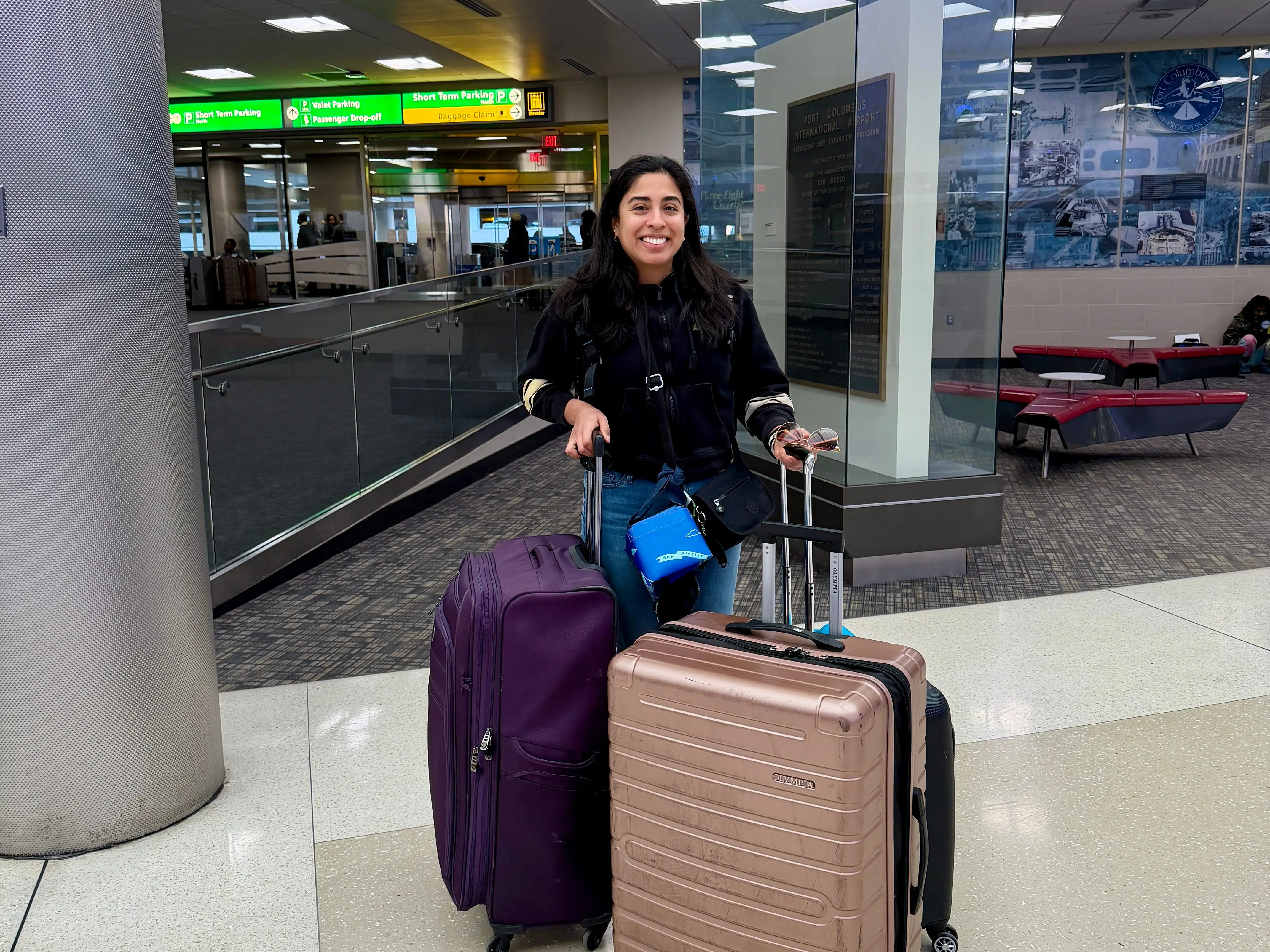 A woman at the airport with two suitcases.