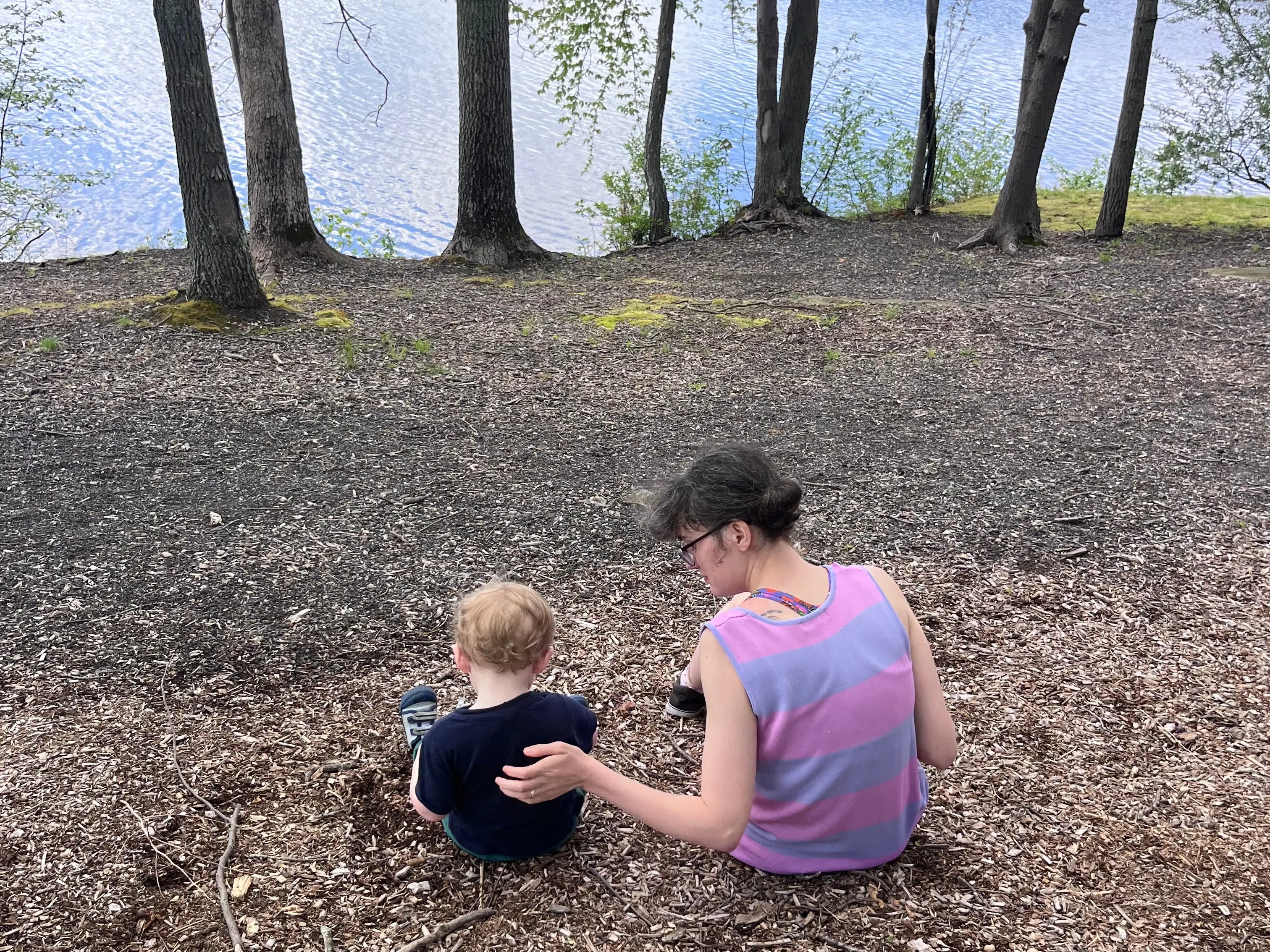 Back of woman and young boy sitting in woods